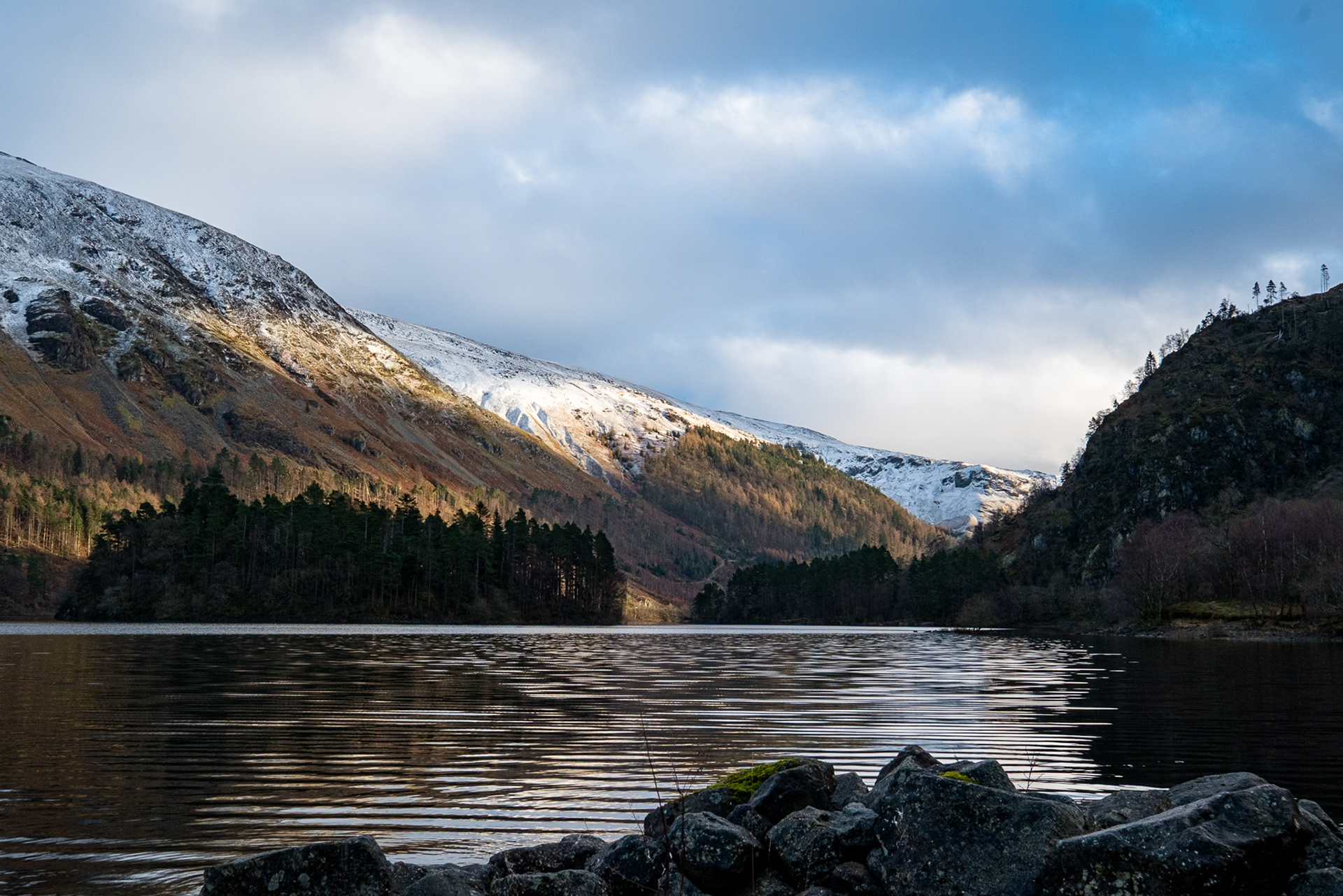 Winter storm clouds gather over the snow capped Dollywaggon Pike and Thirlmere Reservoir, Cumbria.