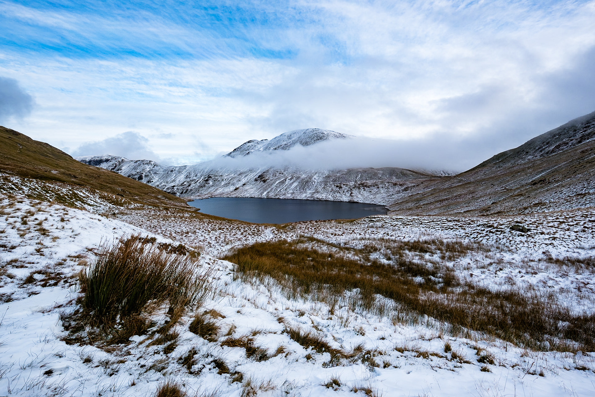 A winter scene high in the lakeland Fells showing a cloud flanked St Sundays Crag.  Grisedale Tarn can be seen in the middle distance..