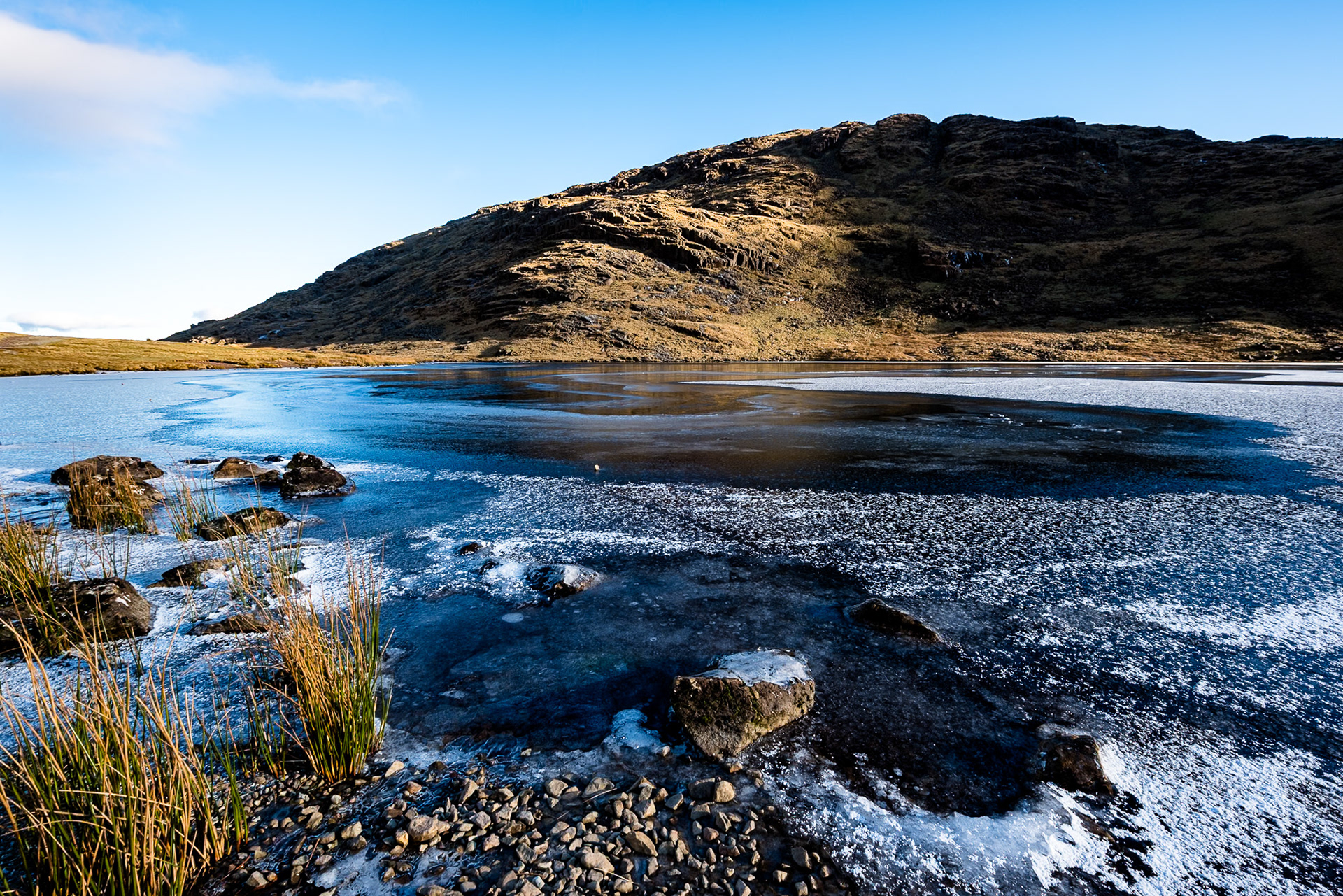 Seathwaite Fell towers above a frozen Styhead Tarn.