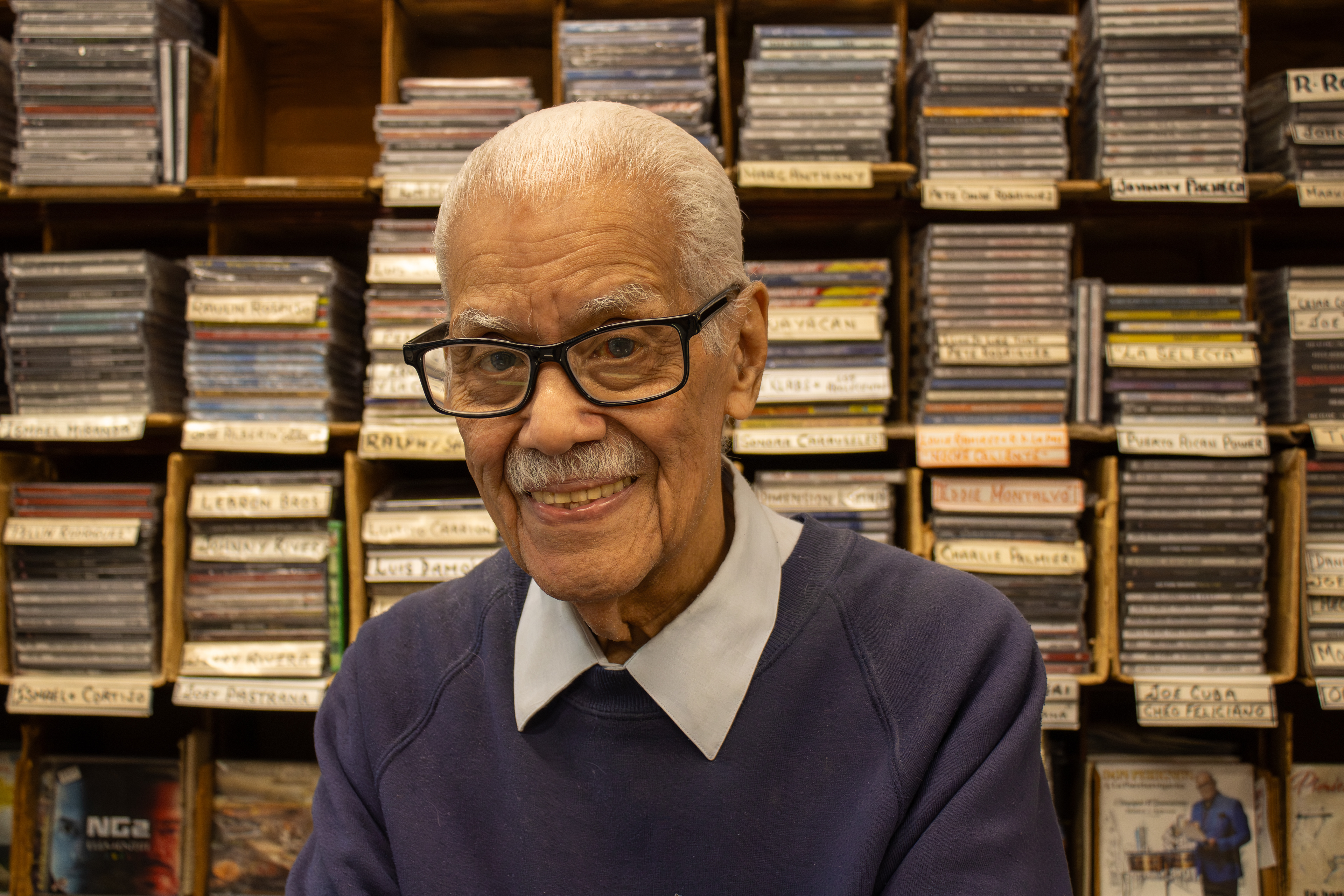 Mike Amadeo poses inside Casa Amadeo in The Bronx on May 9, 2026. At 92 years old, his shop was added to the National Register of Historic Places in 2001, serving New York's Puerto Rican community for over 85 years.