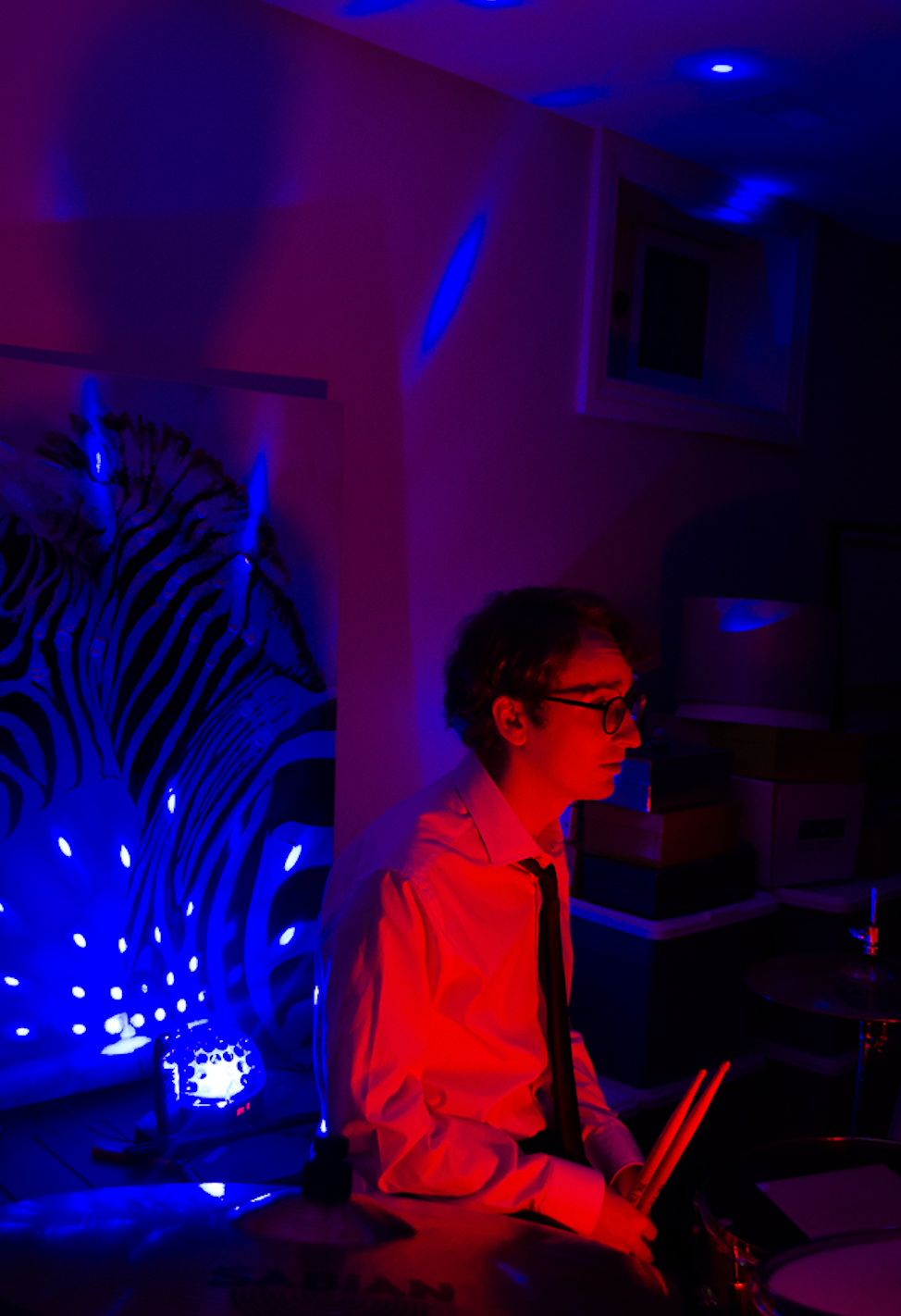 Caption: Andy Wright, drummer and songwriter for the Toronto-based band People Less Qualified, pauses between tracks during a dimly lit rehearsal session in Toronto on Saturday, Feb. 21, 2026. The musician used the evening practice to refine material for his new EP, marking his first time rehearsing since a recent breakup. Camera Settings: 1/30, ISO 1000, f/4.0