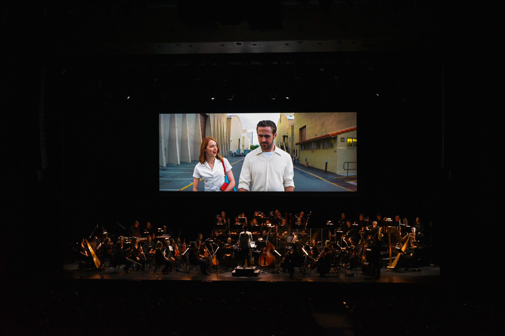 Caption: The entire orchestra looks up to watch a scene of “La La Land” that does not have accompanying music at Meridian Hall in Toronto on Saturday, March 7, 2026. Camera Settings: 1/125, ISO 6400, f/2.8
