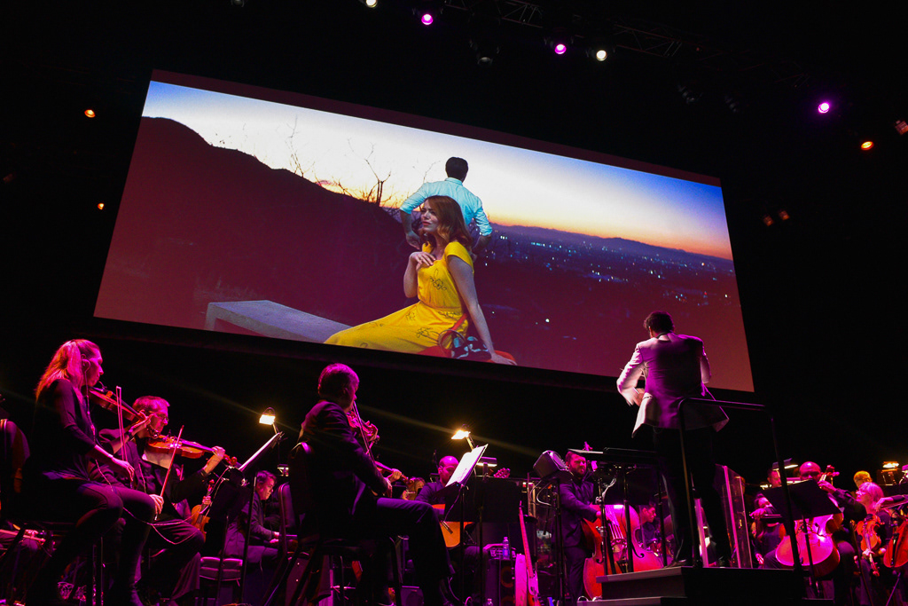 Caption: Conductor Justin Hurwitz cues the strings section during the iconic “A Lovely Night” dance sequence at a “La La Land” concert screening at Meridian Hall in Toronto on Saturday, March 7, 2026. Camera Settings: 1/60, ISO 4000, f/2.8