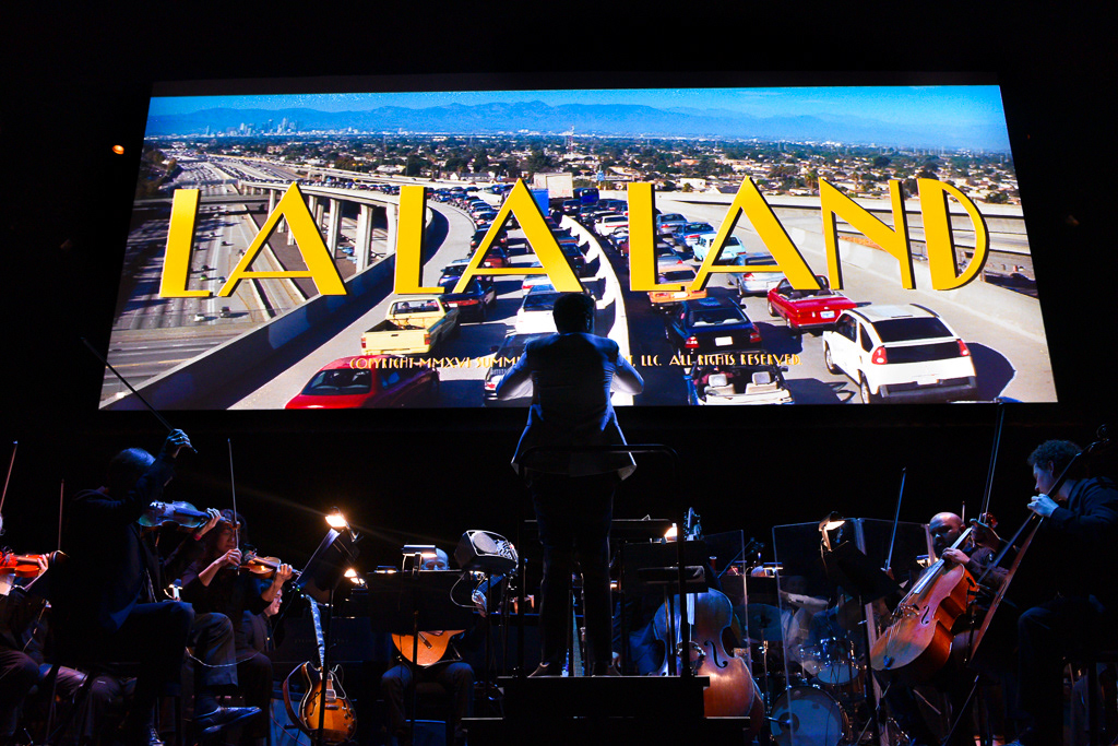 Caption: Conductor Justin Hurwitz leads the orchestra through the film’s opening sequence during a “La La Land” concert screening at Meridian Hall in Toronto on Saturday, March 7, 2026. The audience clapped along with electric energy as the live music synchronized with the cinematic highway scene. Camera Settings: 1/60, ISO 2800, f/2.8