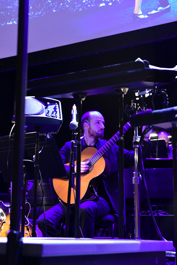Caption: A guitarist plays alongside a jazz band and full orchestra during a "La La Land" concert screening at Meridian Hall in Toronto on Saturday, March 7, 2026. The musician performed the film's acclaimed soundtrack to a sold-out crowd after overwhelming local demand prompted the tour to add a 2 p.m. matinee. Camera Settings: 1/40, ISO 6400, f/2.8