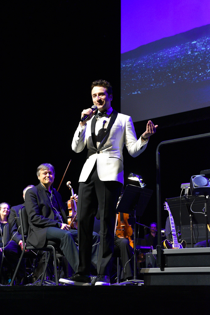 Caption: Composer Justin Hurwitz addresses the crowd before conducting a live orchestra during a surprise appearance at a “La La Land” concert screening at Meridian Hall in Toronto on Saturday, March 7, 2026. The Academy Award-winning composer surprised the audience at the 2 p.m. matinee, sharing his love for the city and recalling the film’s original debut alongside director Damien Chazelle at the Toronto International Film Festival. Camera Settings: 1/125, ISO 1600, f/2.8