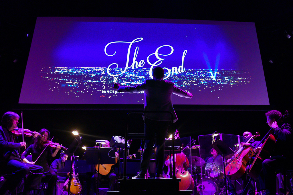 Caption: Conductor Justin Hurwitz holds his arms wide as the film concludes to a standing ovation during a “La La Land” concert screening at Meridian Hall in Toronto on Saturday, March 7, 2026. The audience erupted in applause as the final “The End” title card illuminated the auditorium. Camera Settings: 1/50, ISO 1600, f/2.8