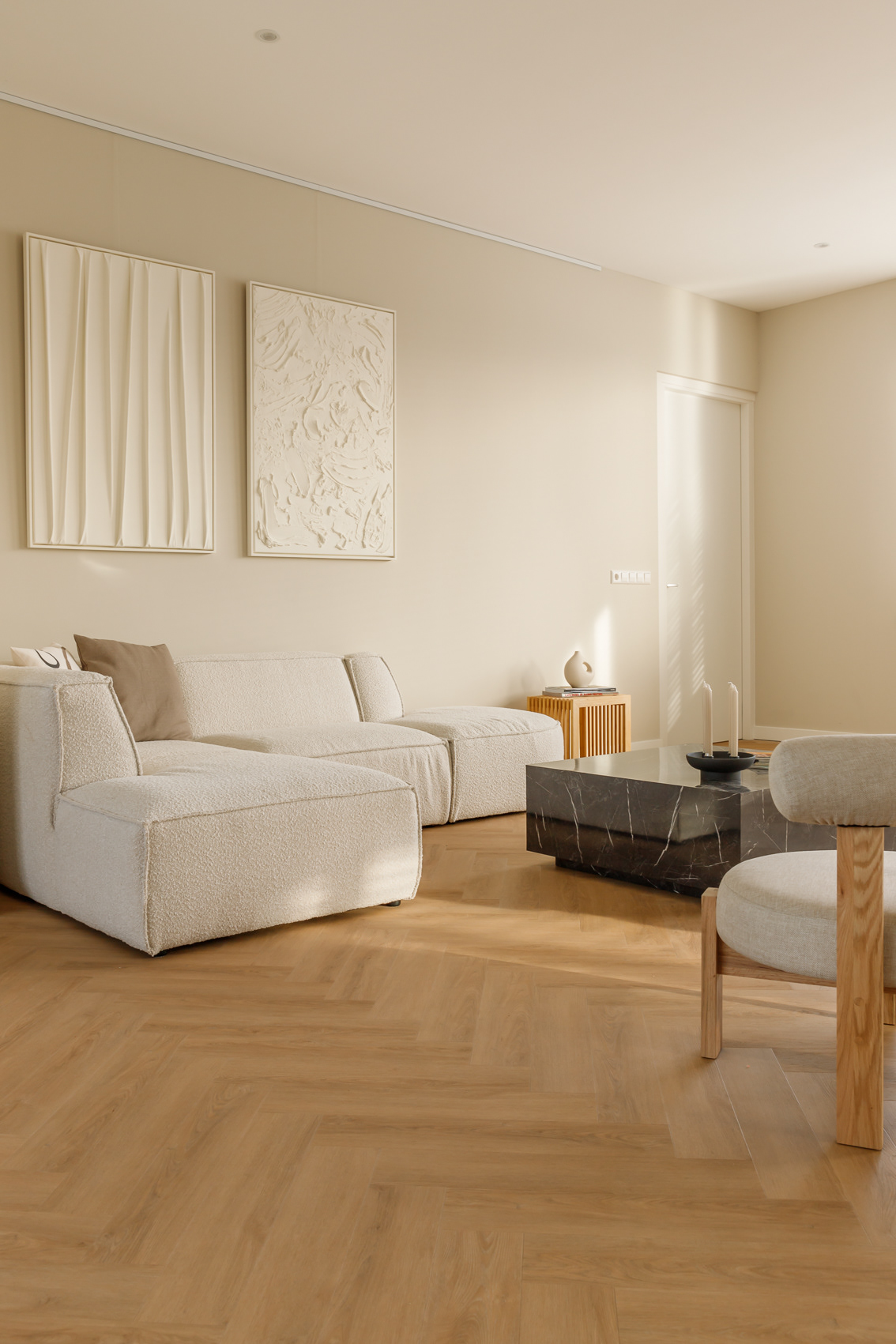 interieurfoto van beige woonkamer met witte bank, schilderijen en marmeren tafel