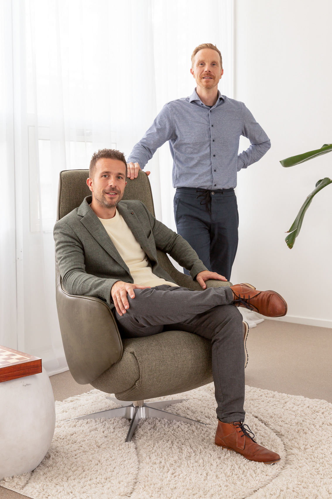 Twee mannen waarvan een op stoel en een staand een interieur