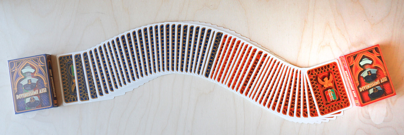 Divinissimi Assi Blue and Red deck boxes with ribbon display of playing cards showing both back designs.