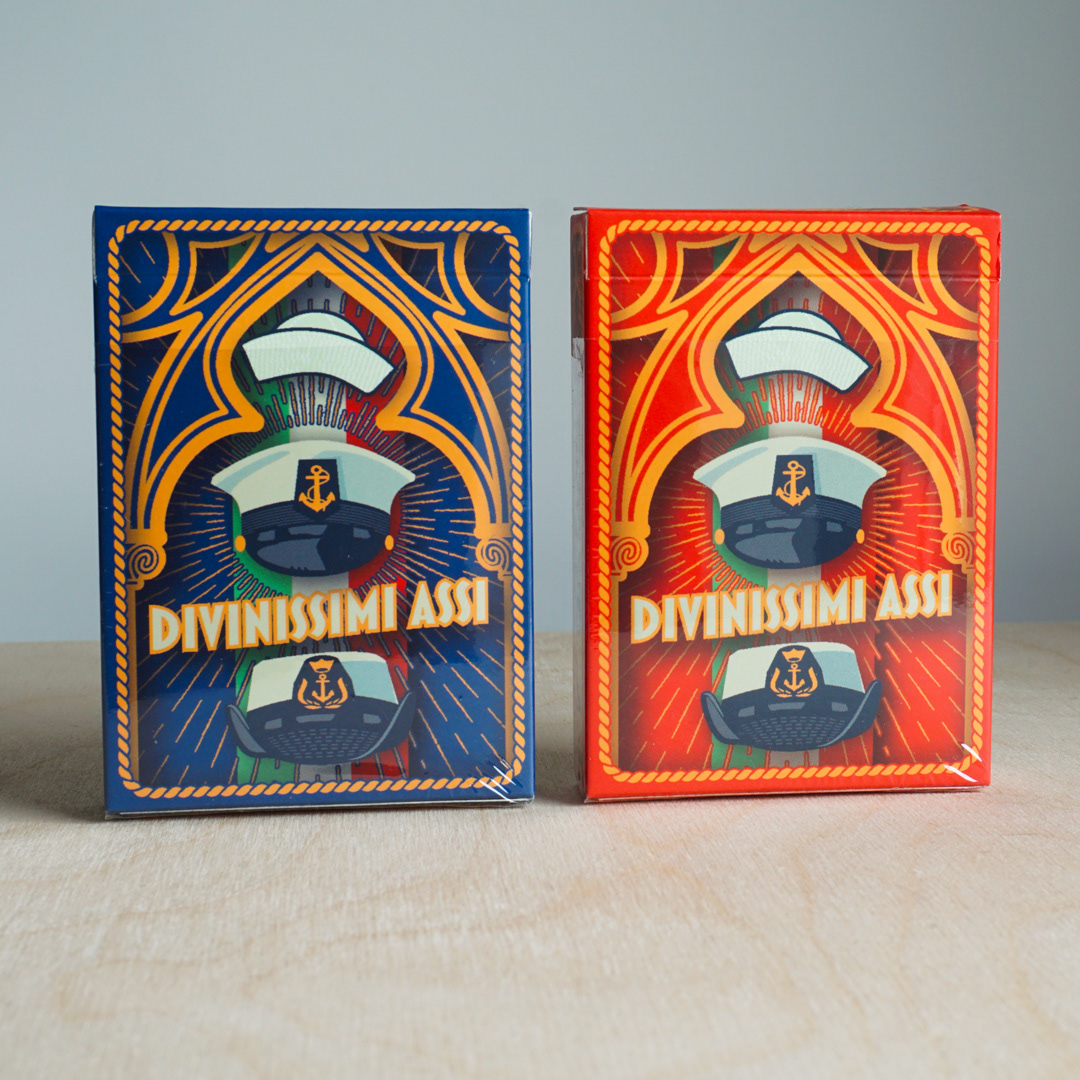Blue and red Divinissimi Assi deck boxes side by side — Italian-designed collectible playing cards by CalamoVe.