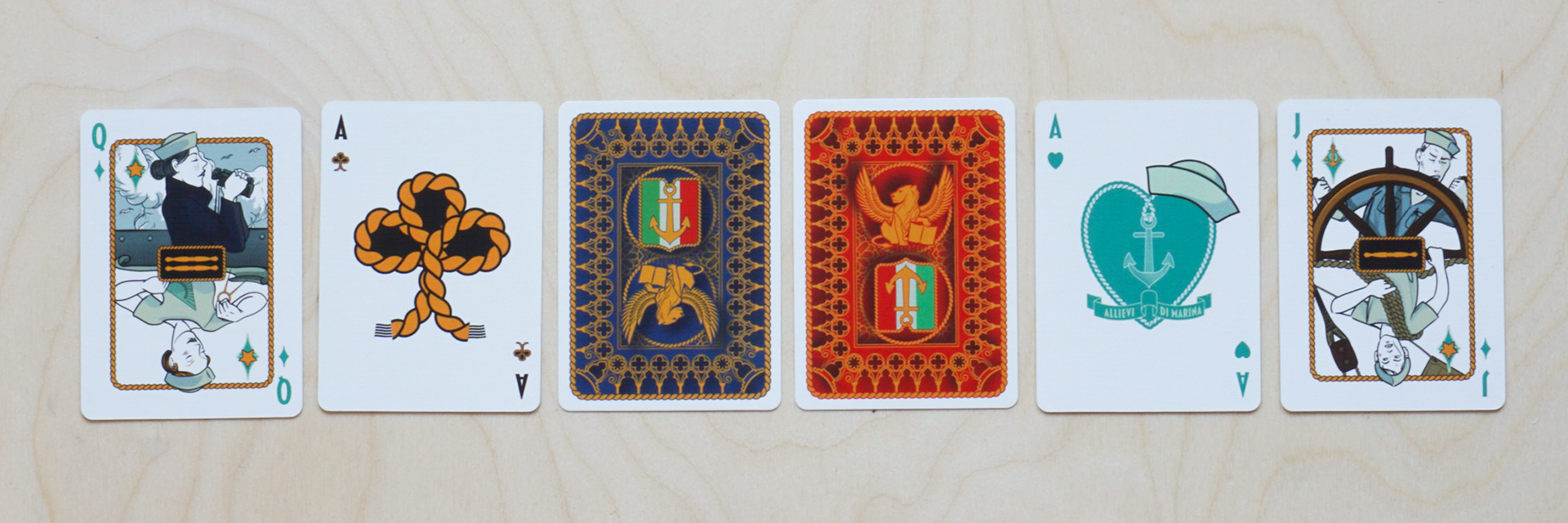 Divinissimi Assi playing cards — Blue and Red editions with visible backs and face cards including the Ace of Clubs, Ace of Hearts, Jack and Queen of Diamonds.