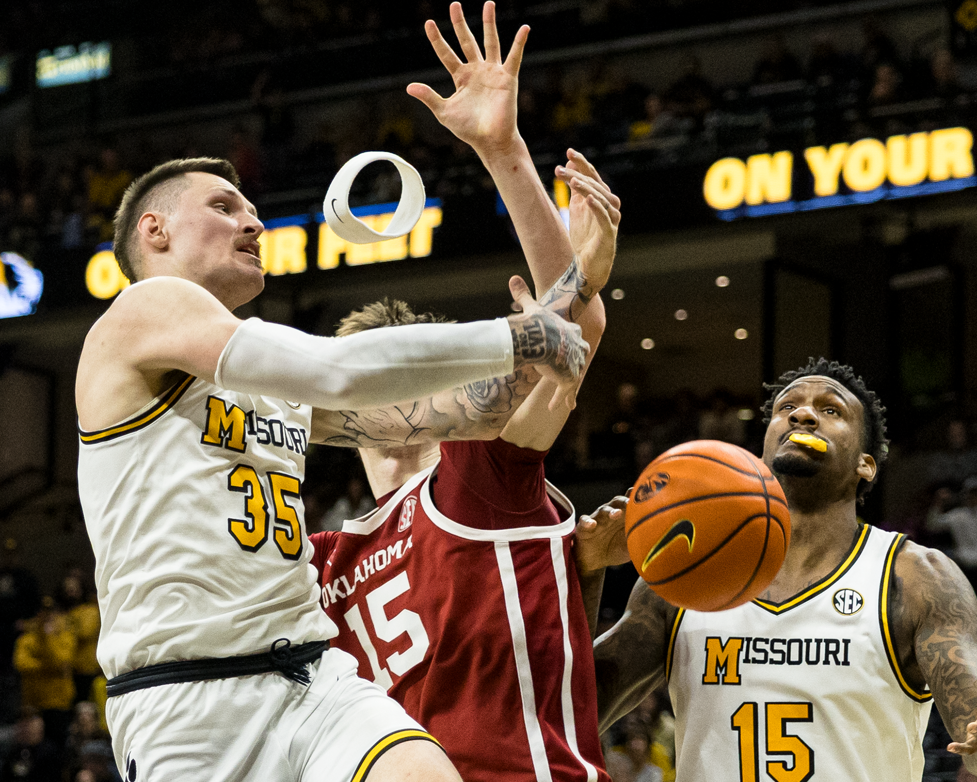 From left, Mizzou guard Jacob Crews (35) has his headband knocked off as Oklahoma center Kirill Elatontsev (15) tries to grab the basketball and Mizzou center Shawn Phillips Jr. (15) gets his mouth guard knocked out at Mizzou Arena on January 24, 2026 in Columbia, Missouri.