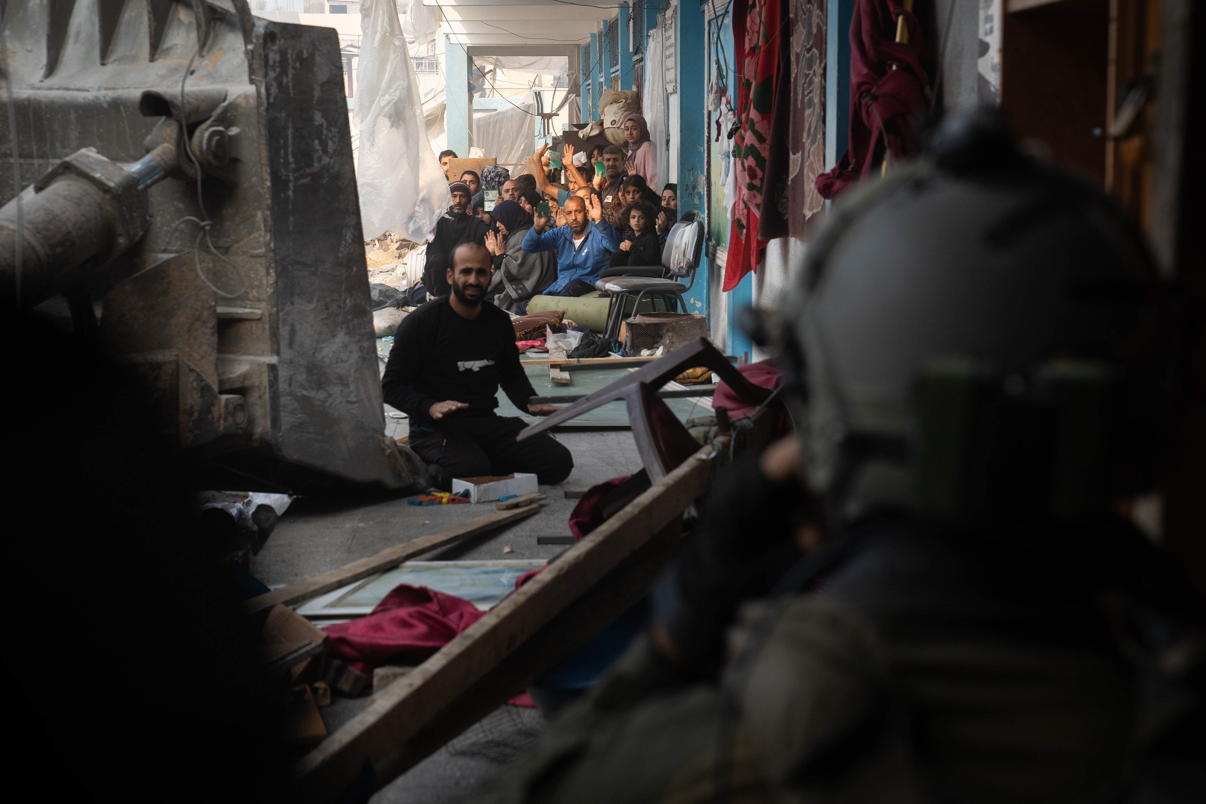 Soldiers calling Gazan civilians to evacuate from a makeshift camp located in a school.