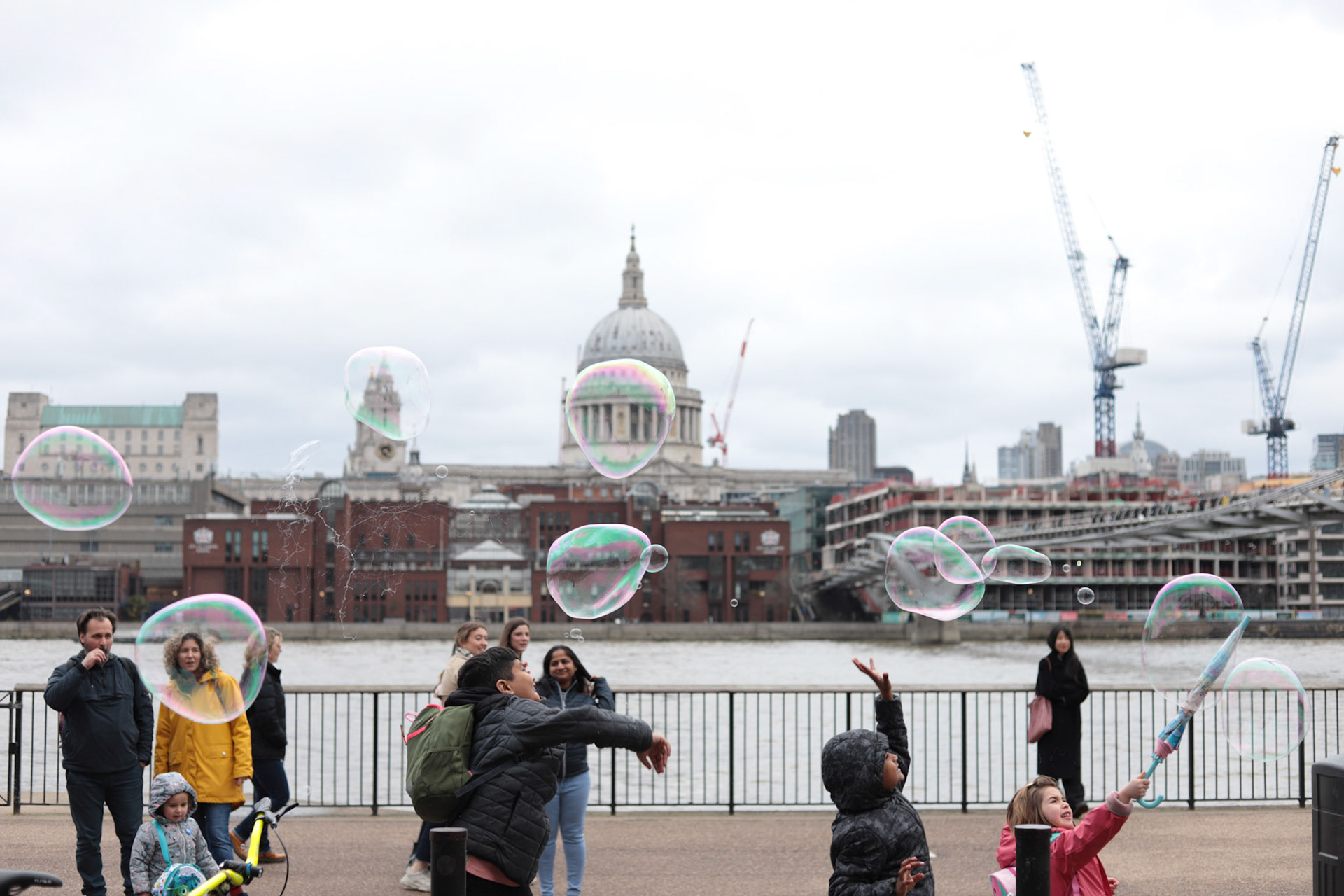 Kids play with bubbles at the entrance of the Tate Modern Museum as Saint Paul's Cathedral is seen across the Thames River in London, Britain, March 26, 2023.