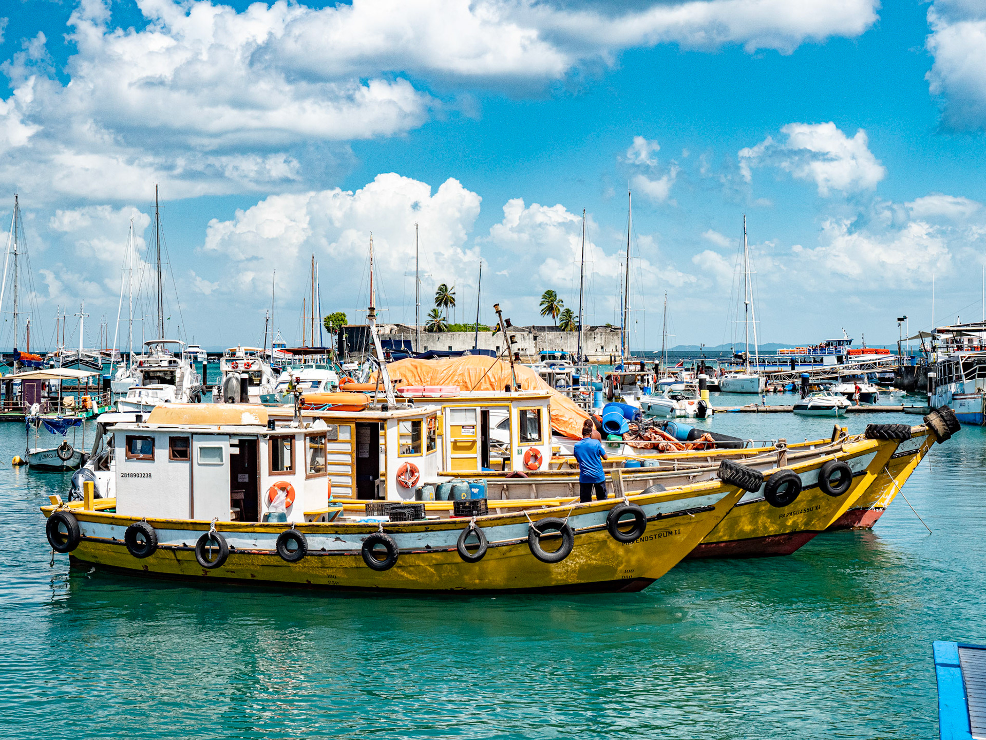 03.02.2025 Salvador de Bahia, Brazil. Colorful fishing boats moored side by side in the Port of Salvador, with Forte de Sao Marcelo in the background