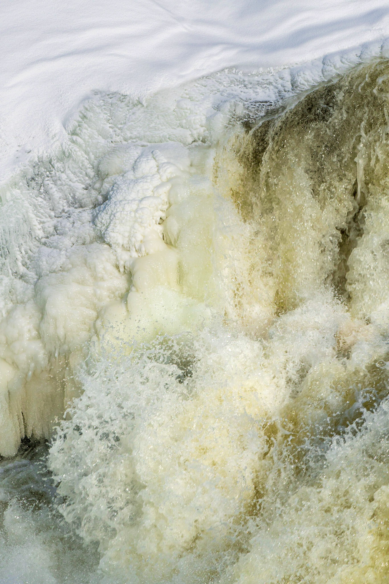 Tumult in the water set against soft flowing lines in the snow. The natural yellow of the water adds to the sense of energy, while the cool blue of the snow evokes serenity.