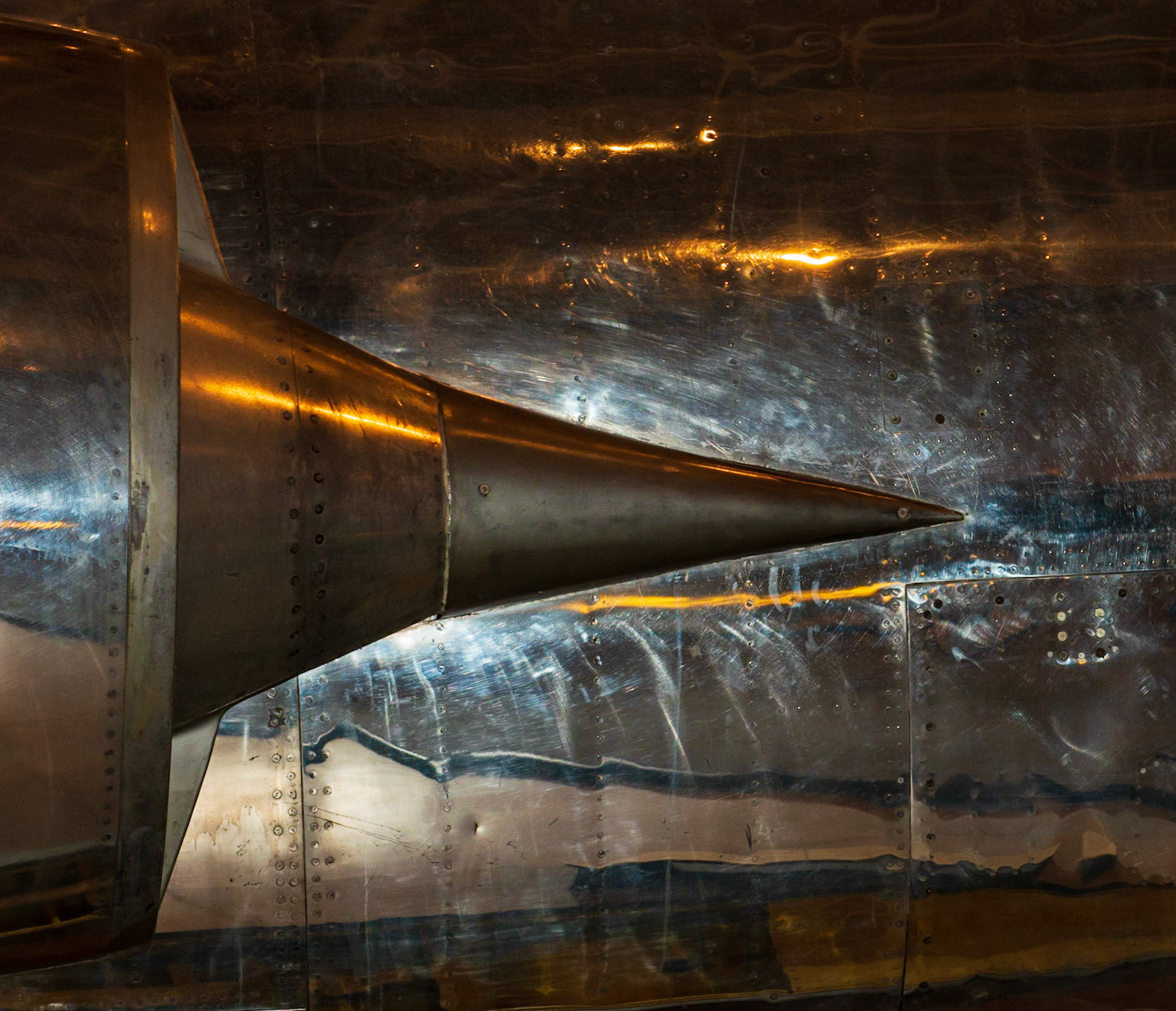 This is the exhaust area of a jet engine but what I see is a strong triangular shape. Light from my flash has lit the background fuselage giving separation to the triangle while museum light adds colour contrast.
