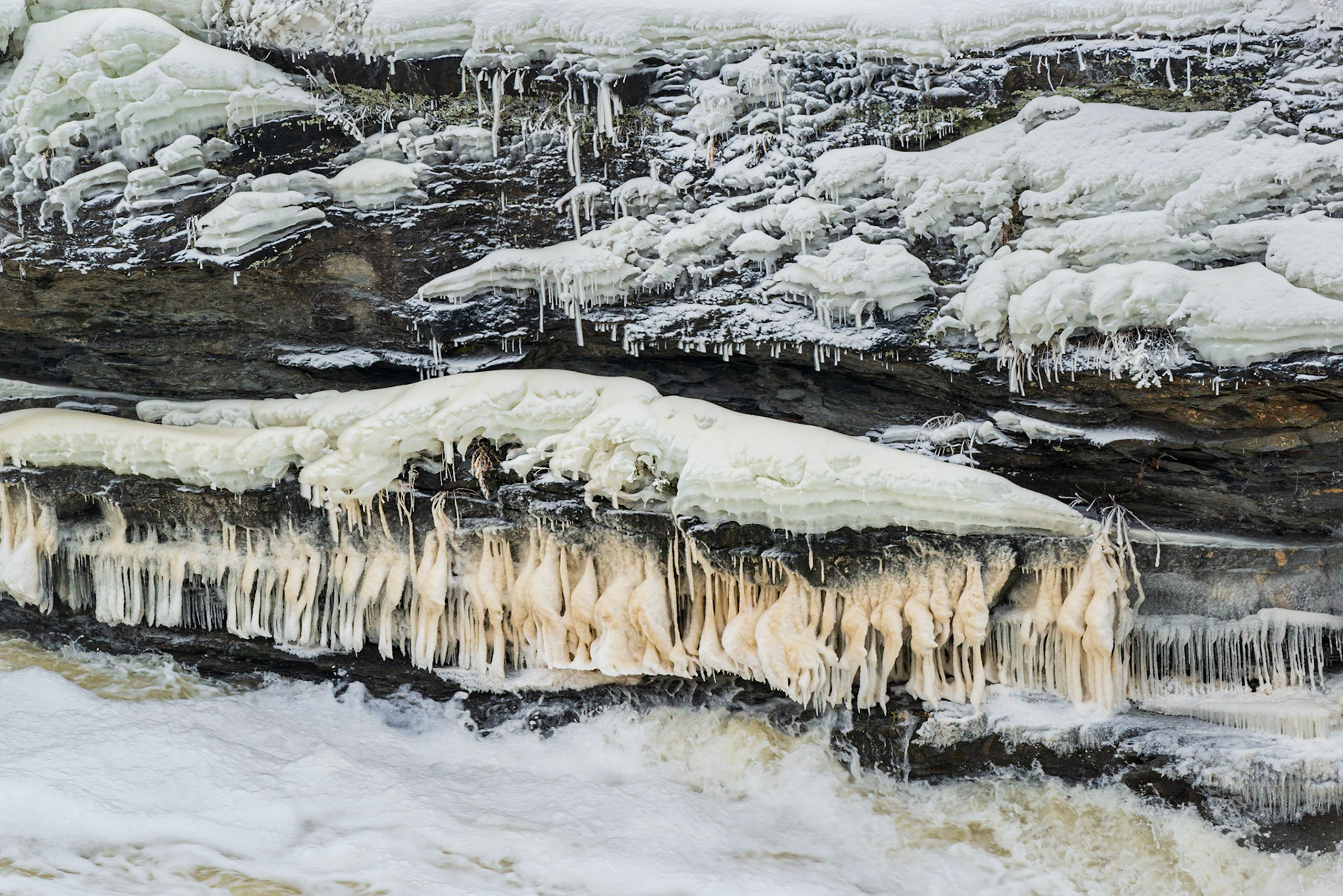 Perhaps it’s just me, but the horizontal line of orange ice formations reminds me of plucked chickens at the butcher shop. Anyway, that’s what drew me to the shot, and I’ve framed them with horizonal layers of ice above and water below.