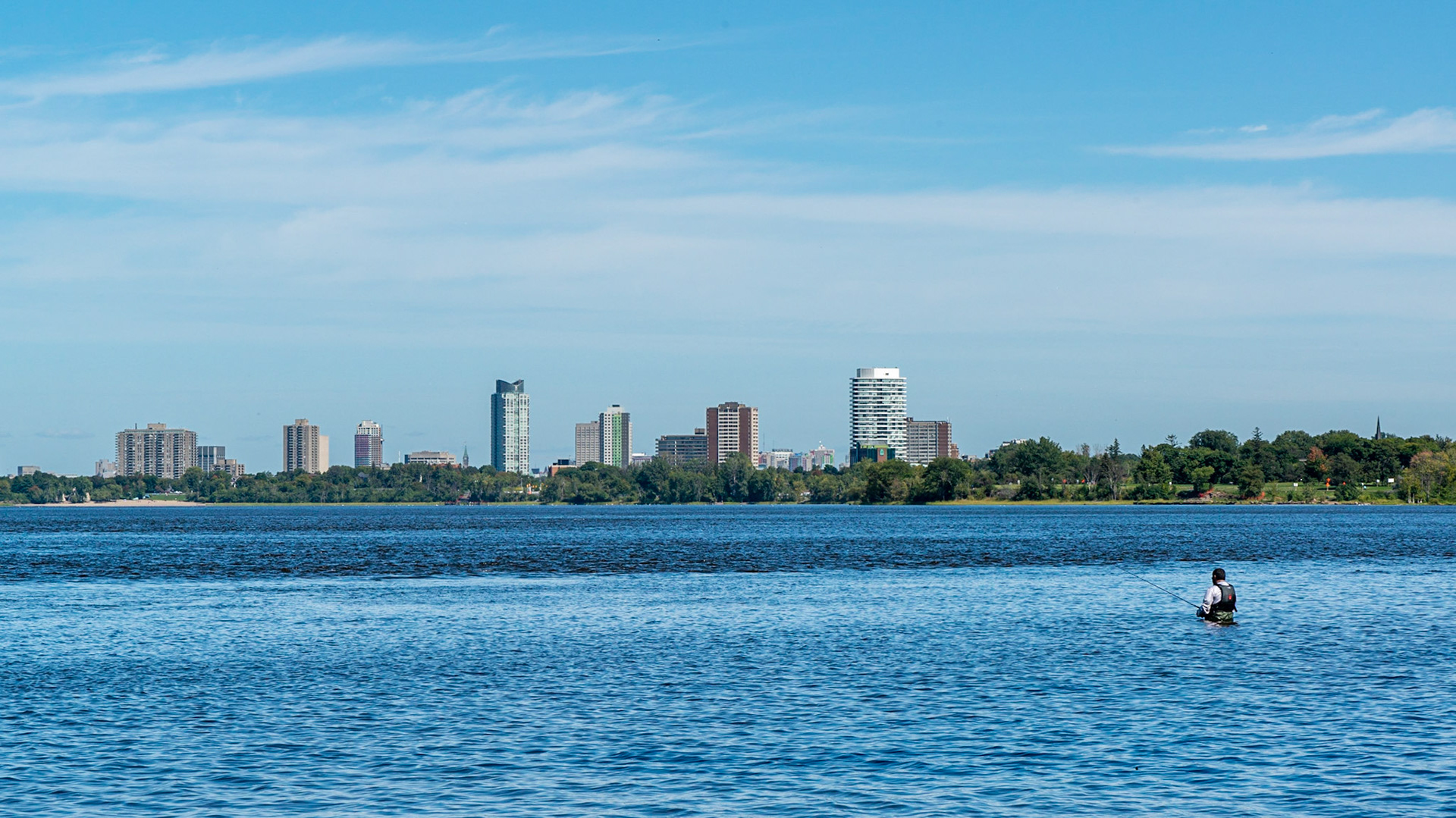 A lone fisherman in the Ottawa River. The Peace Tower is just visible slightly left of centre.