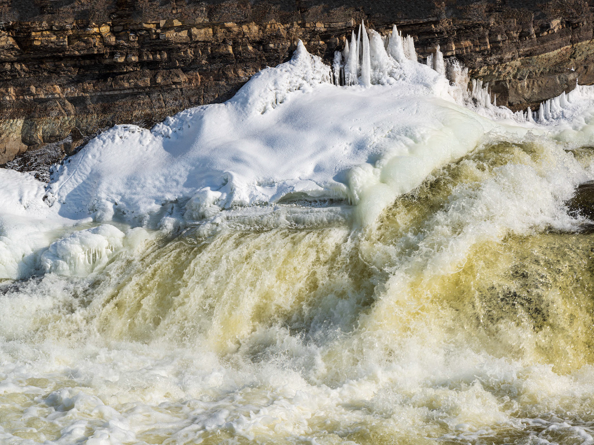 Here we have three layers. The brown rock serves as background. The yellow rushing water provides a foreground. But the main subject are the ice formations on the intermediate strip of snow.