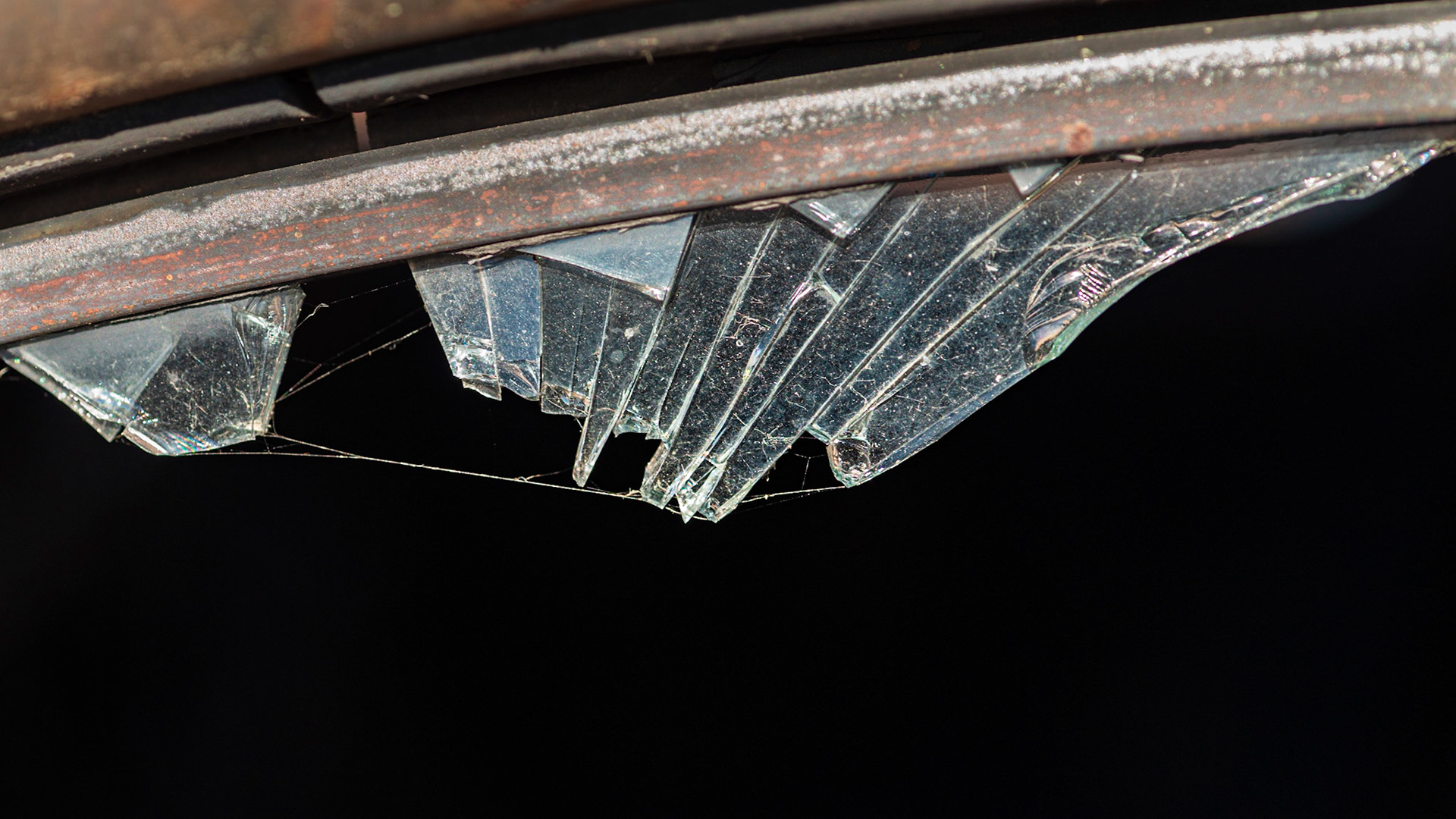 Crystalline fragments of glass radiating from an arc of metal, with some strands of a spider web to add a natural element for contrast. I angled the camera so I had a dark background.