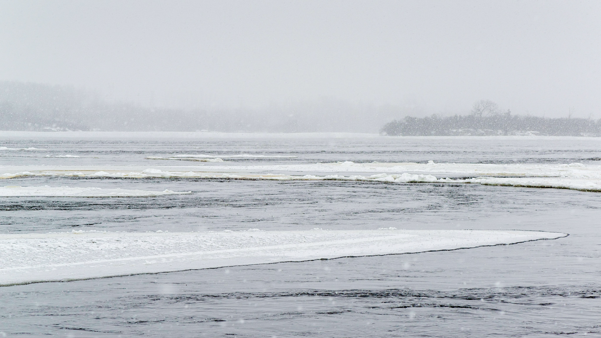 A view along the Ottawa River with a gentle snowfall.