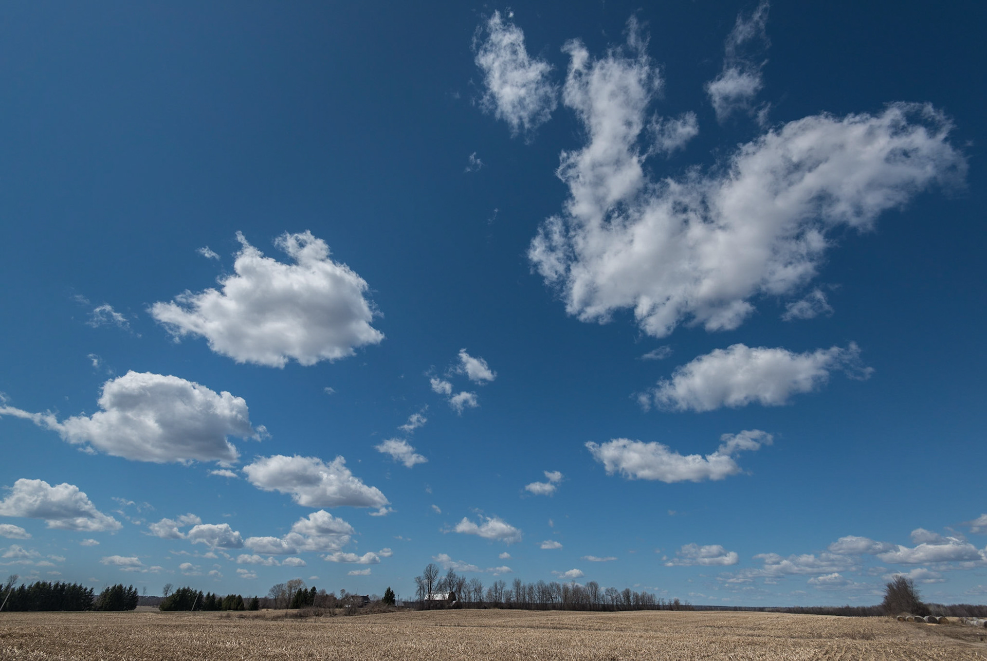 A wide angle shot of clouds over a farmer's field in early Spring