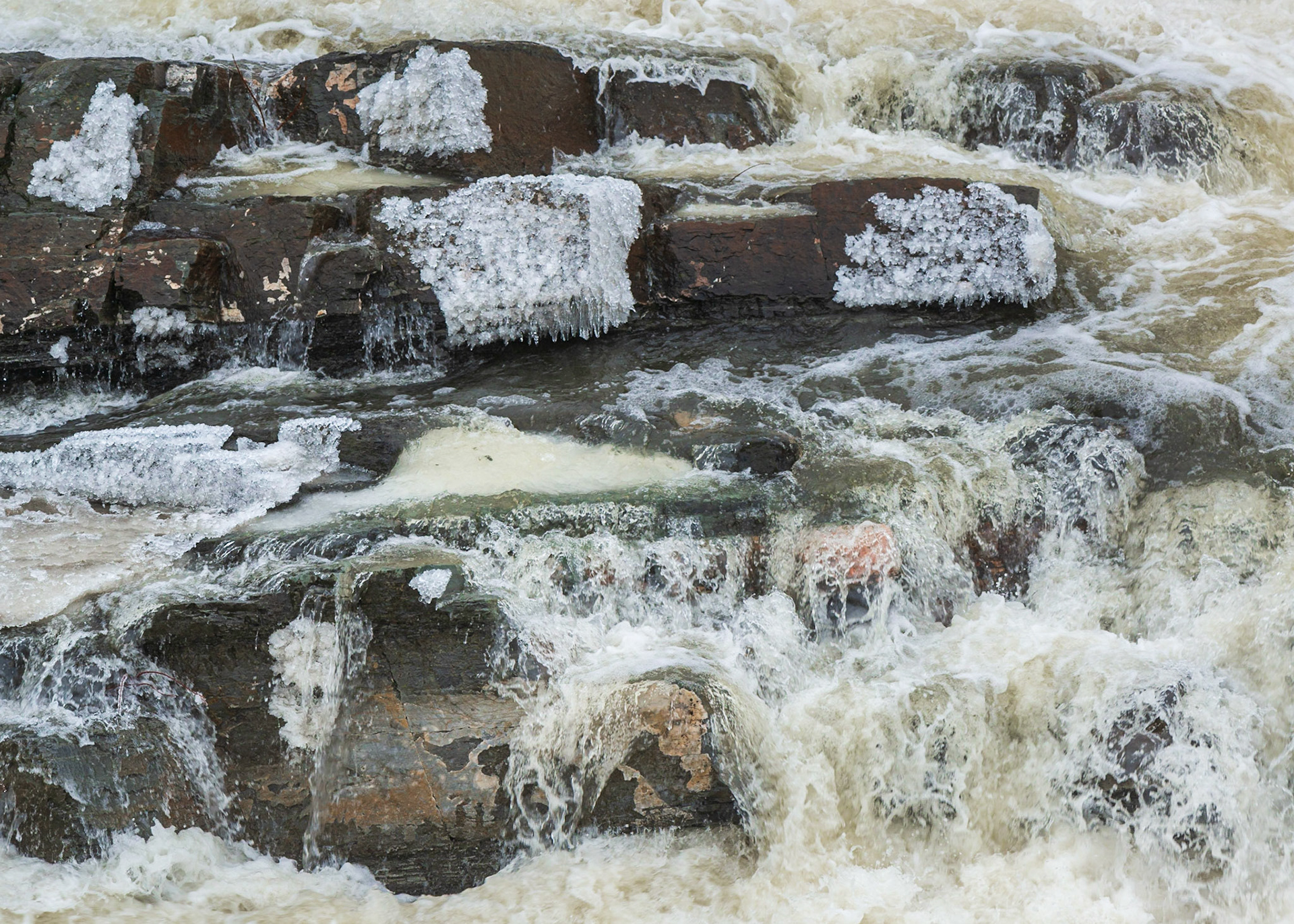 I find the spots of ice in the upper half and orange outcrops in the lower half quite interesting in this shot. There is also some green near the center. I tried to frame all of these in a pleasing way with a sliver of the water at the top and bottom.