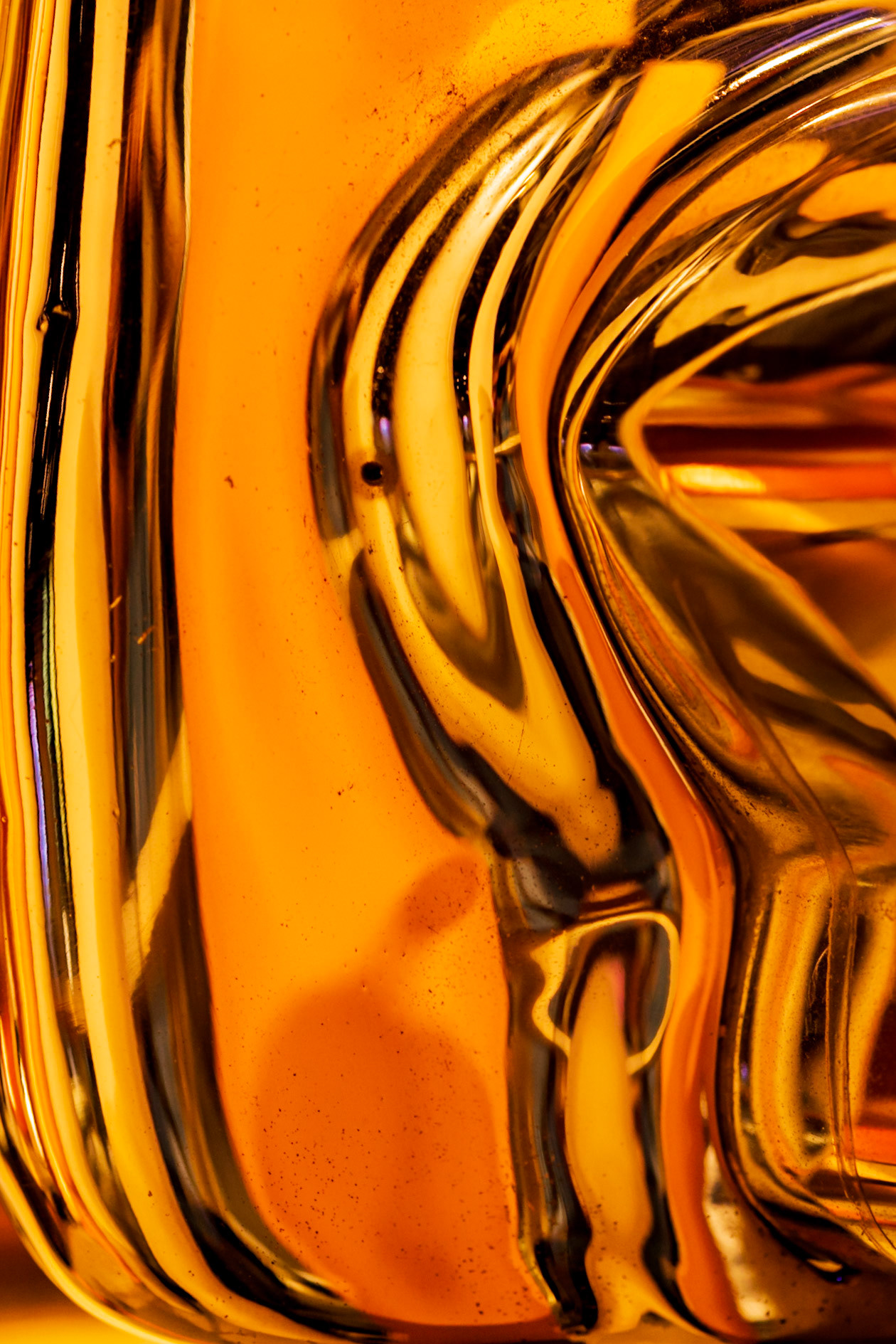 Sometimes interesting abstracts appear in the oddest of places. This is the bumper of a vintage car reflecting the lights, displays and guard rail in its vicinity. I took several shots to explore different compositions.