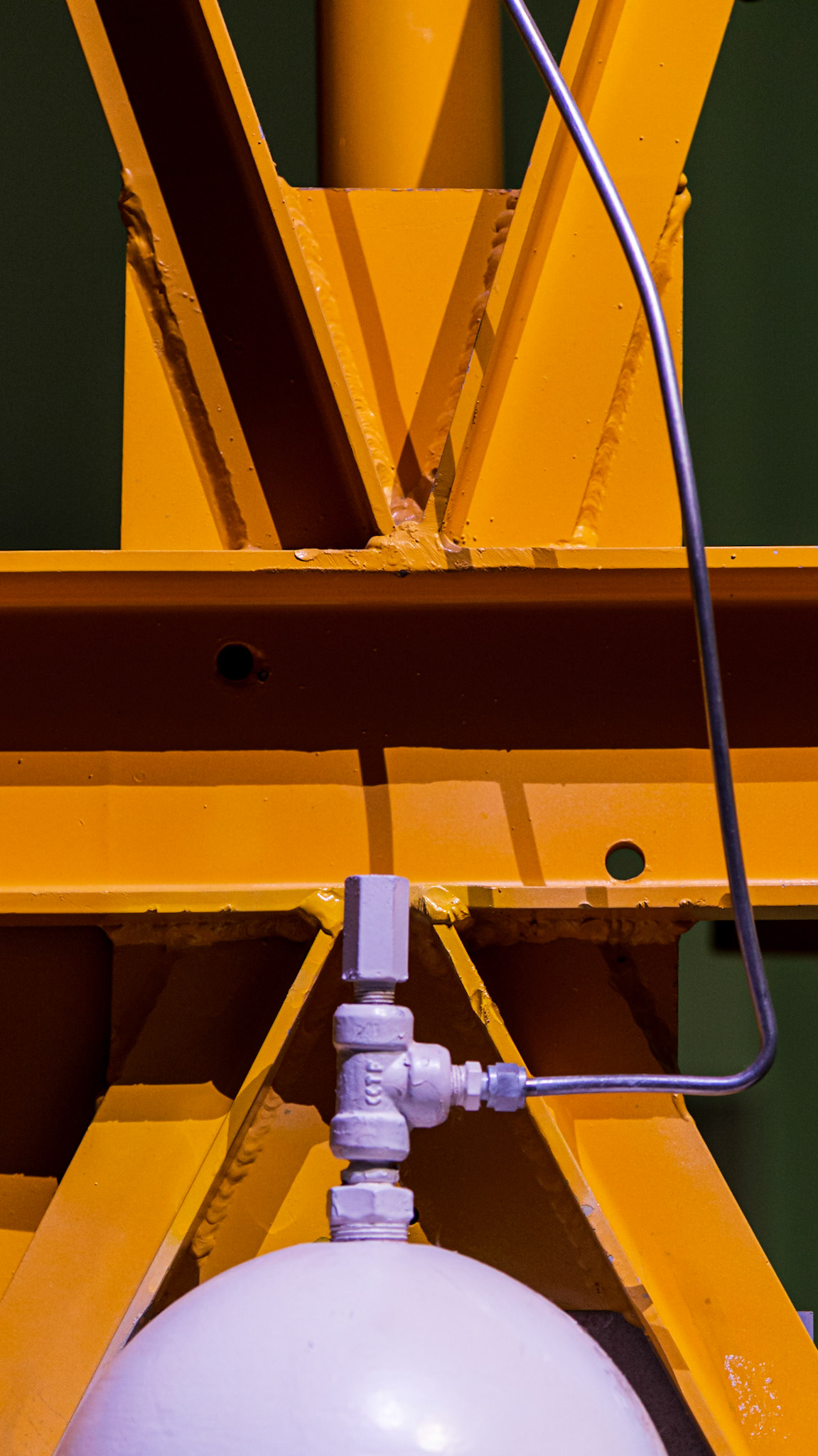 The strong orange X shape is juxtaposed with the soft mauve semicircle contributed by the tank. The tube feeding the tank helps to lead the eye up and down within the frame.