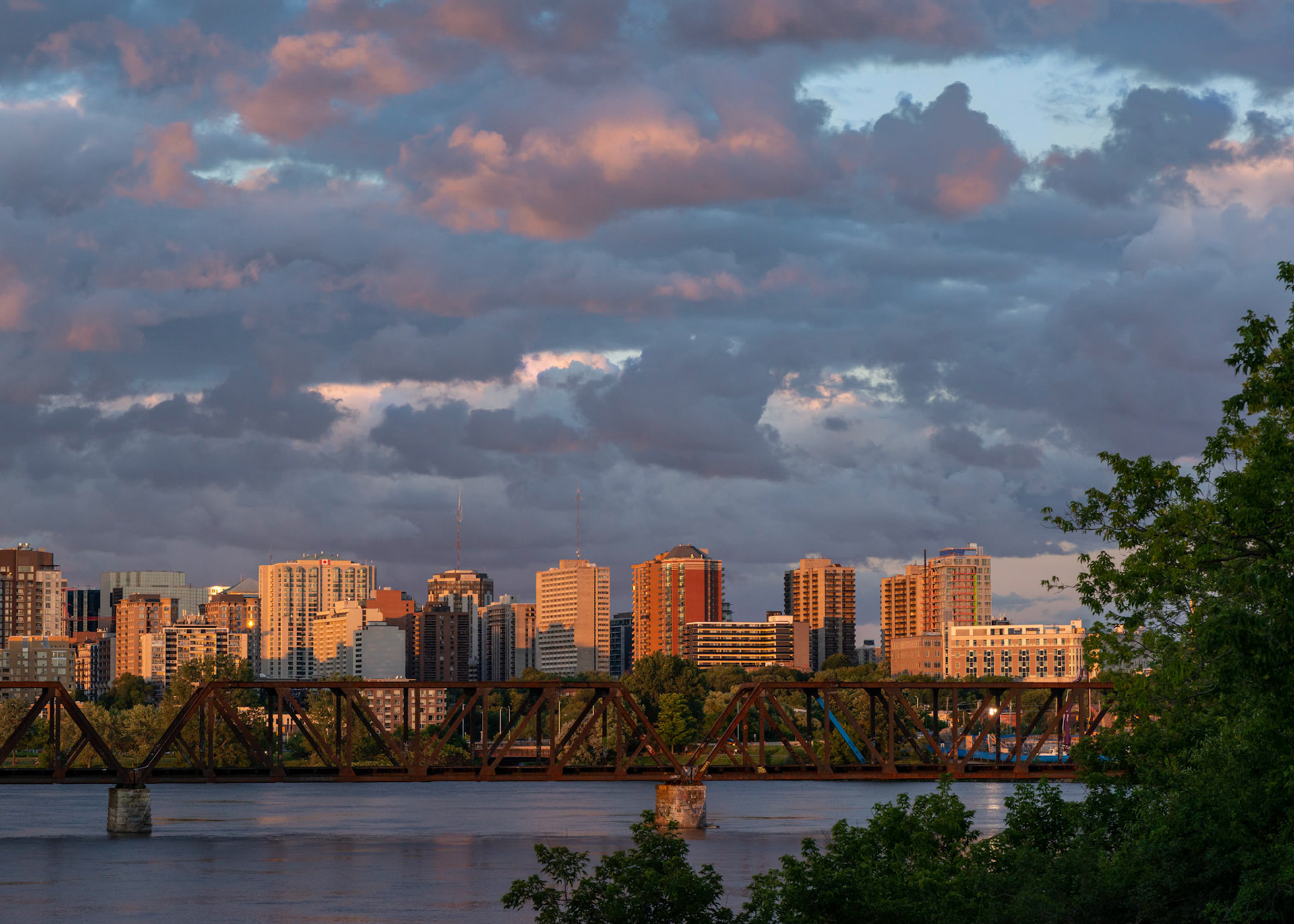 A view of downtown Ottawa from the bridges leading to Lemieux Island. The sunset light draws attention to the buildings and is repeated on the leading edge of the clouds.