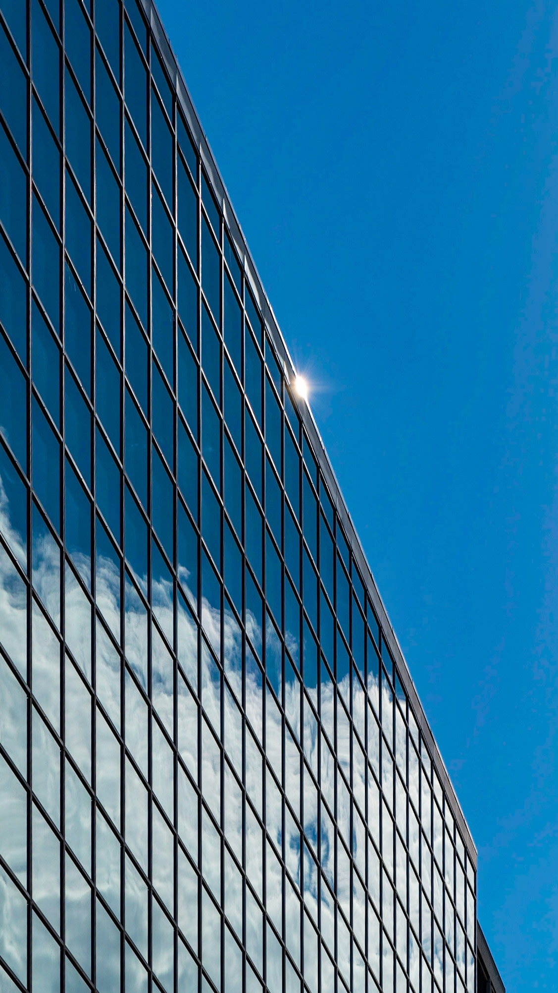 The building and sky divide the frame roughly in half, and the glint of sunlight provides a centre of interest. I tried to choose enough reflected clouds to provide some balance to the composition.