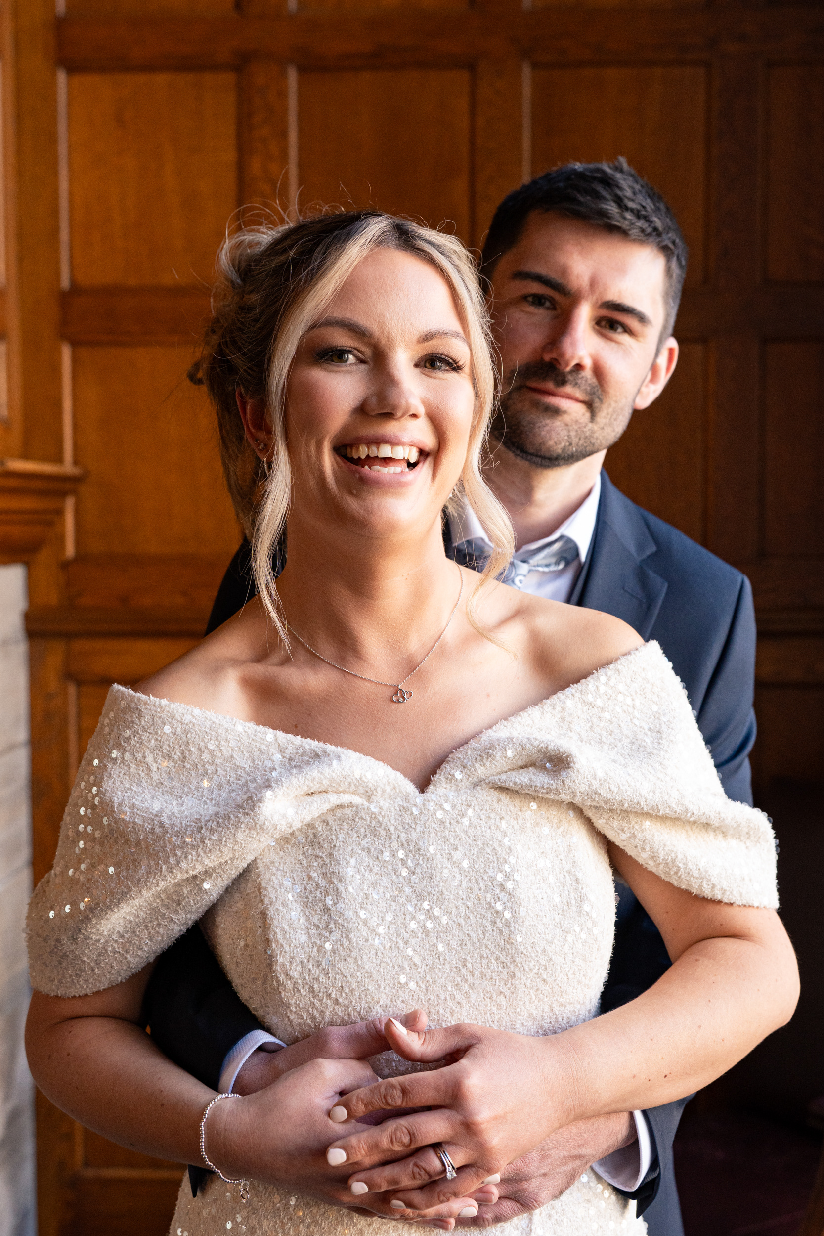 Beautiful bride laughs as her new husband hugs her after their Aberdeen town hall wedding at Marischal College.