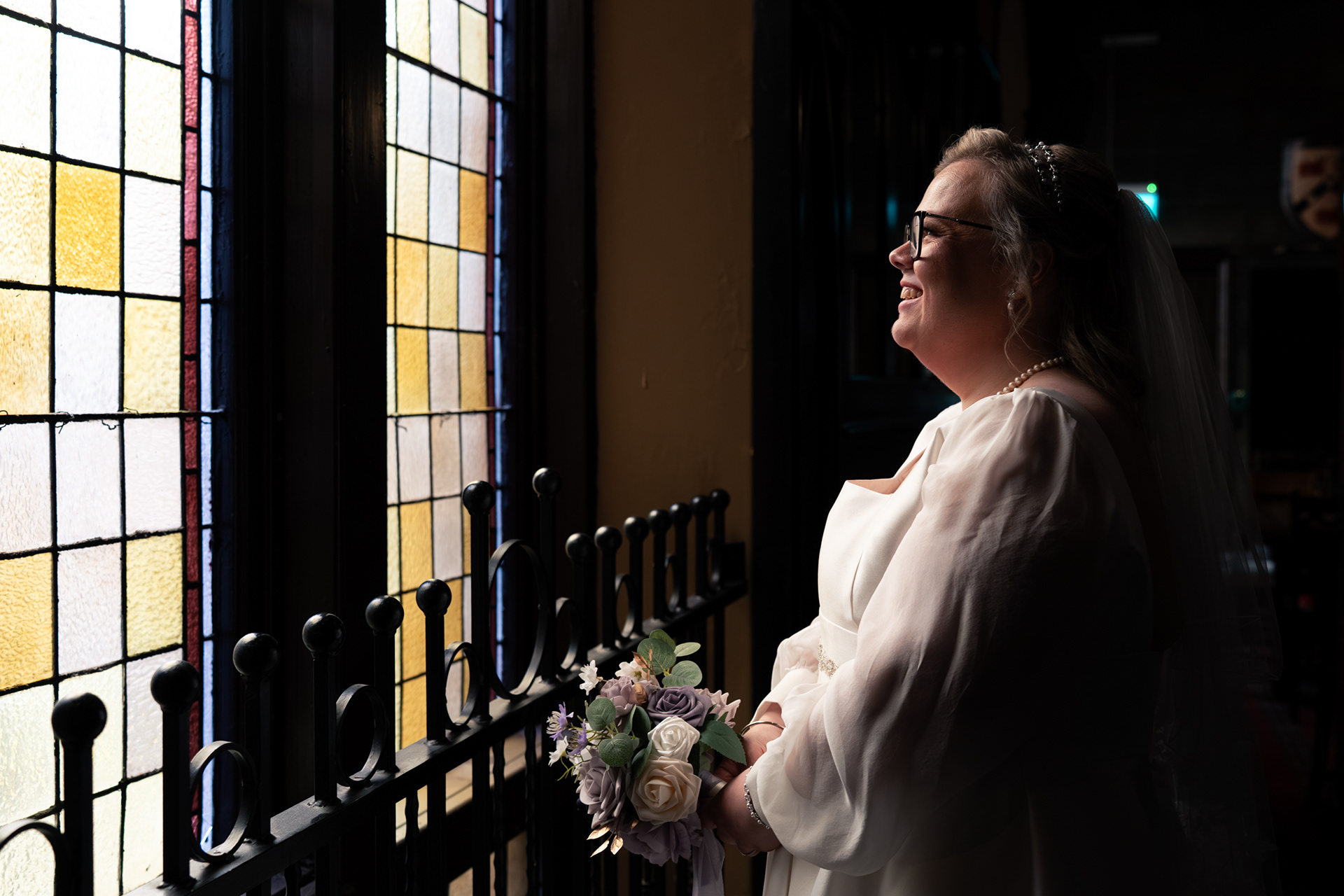 Aberdeen wedding photography: Bride glows in the light of a stained glass window.