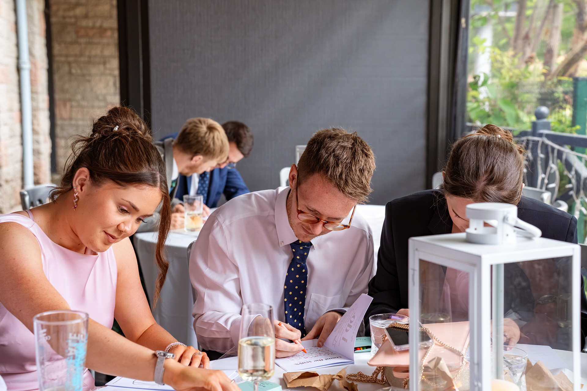 Two women and a man are very focused on the workbooks in front of them.