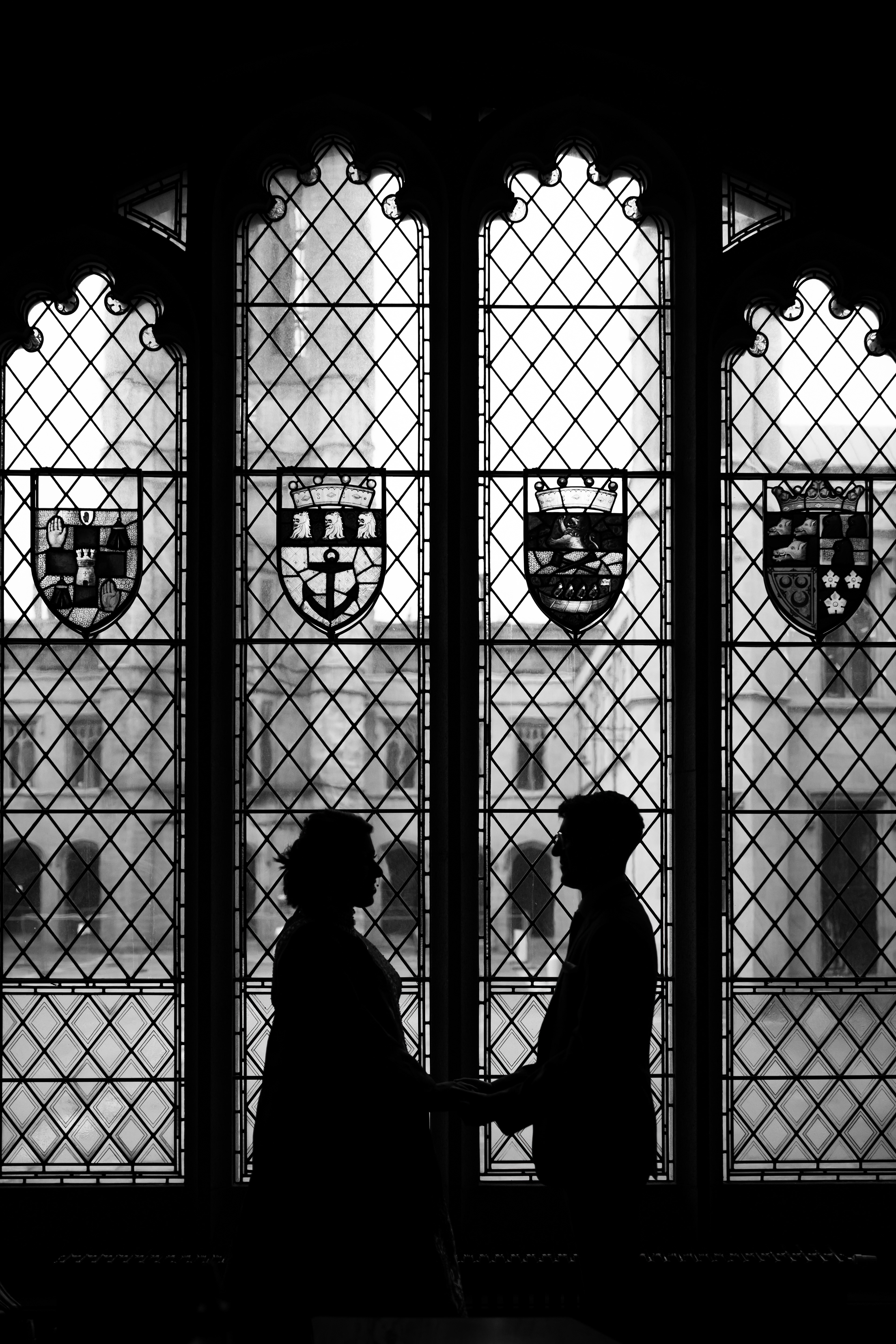 Aberdeen Wedding Photography: Black and white photo of a newlywed couple silhouetted against the stained glass window in Marischal College.