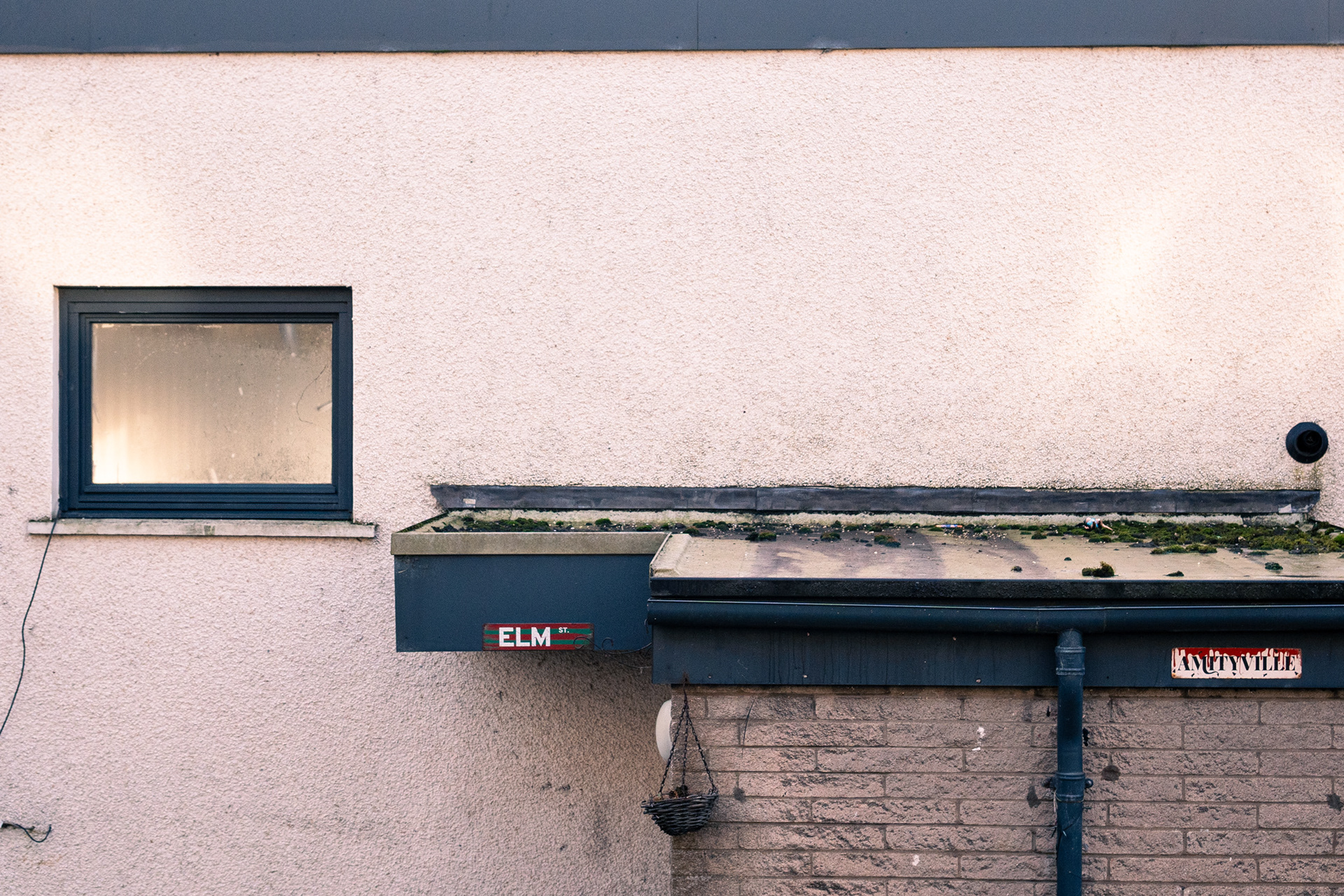 Signs reading "Elm St" and "Amityville" are positioned above a rundown porch.