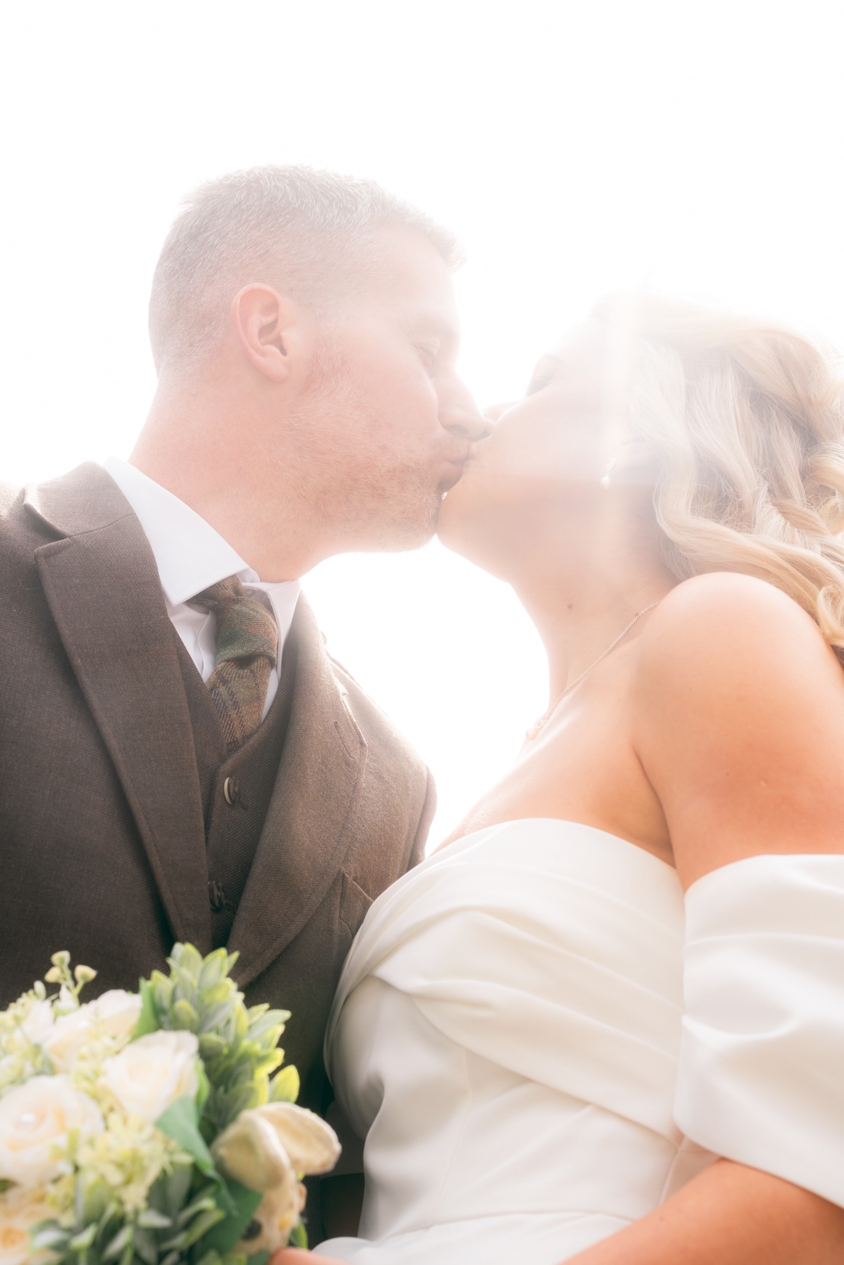Bride and groom kiss in sun flare on Broad Street, outside Marischal College.