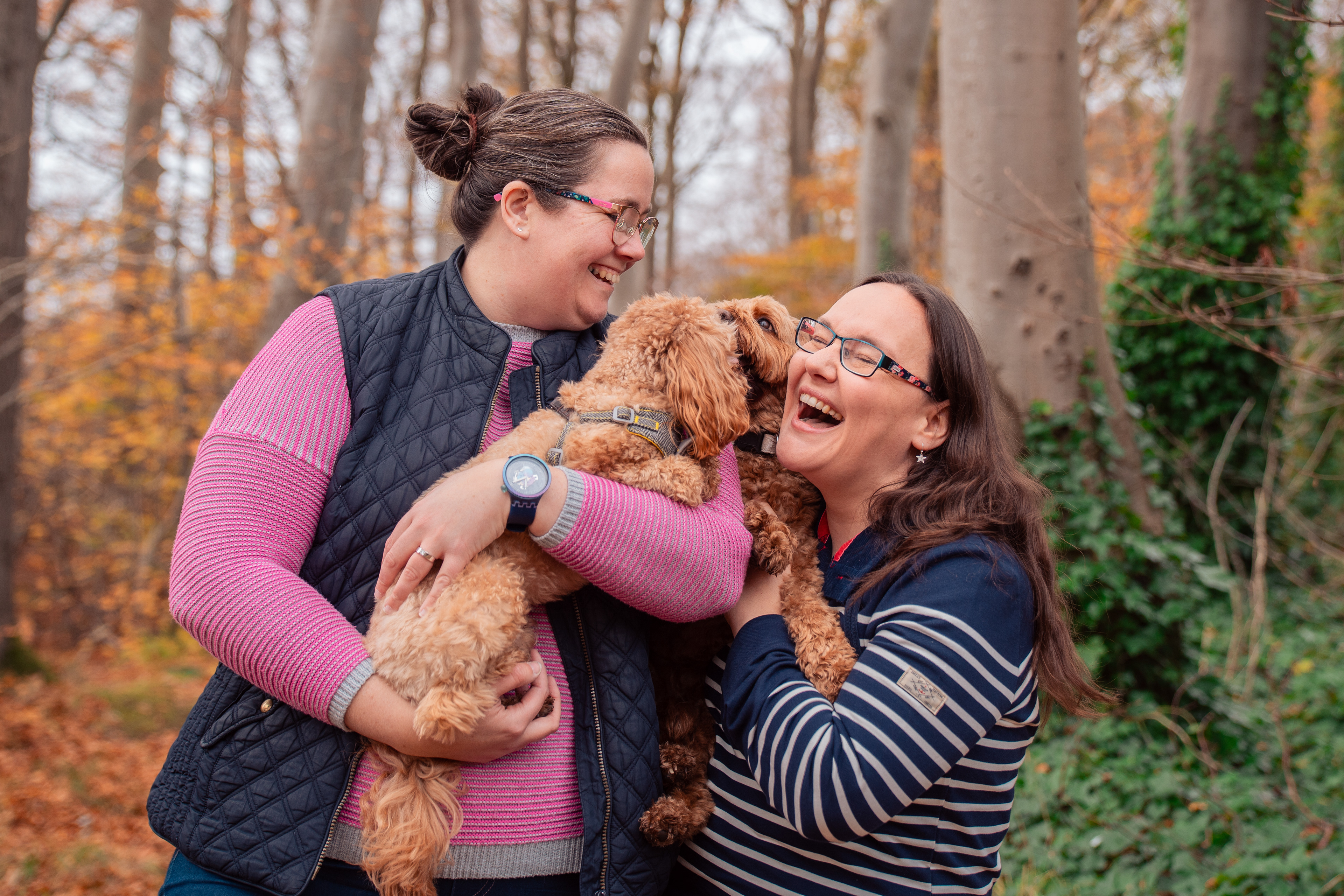 At their Aberdeen engagement photo shoot, two brunette women in stripy tops and glasses laugh as their small dogs try to join in with the cuddles