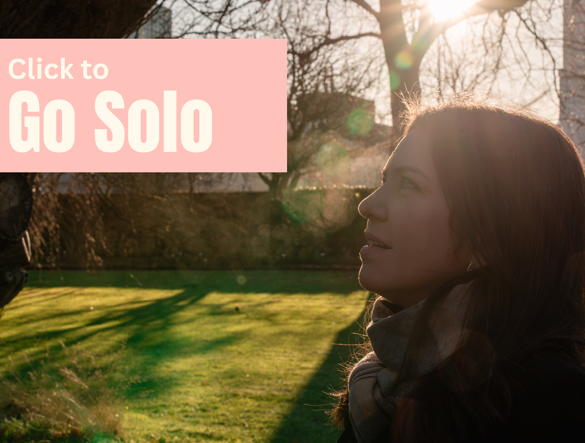 On a winter's day, a white woman with long dark hair breathes clouds out of her mouth as she is backlit by the sun. The overlaid text reads "Click to Go Solo".