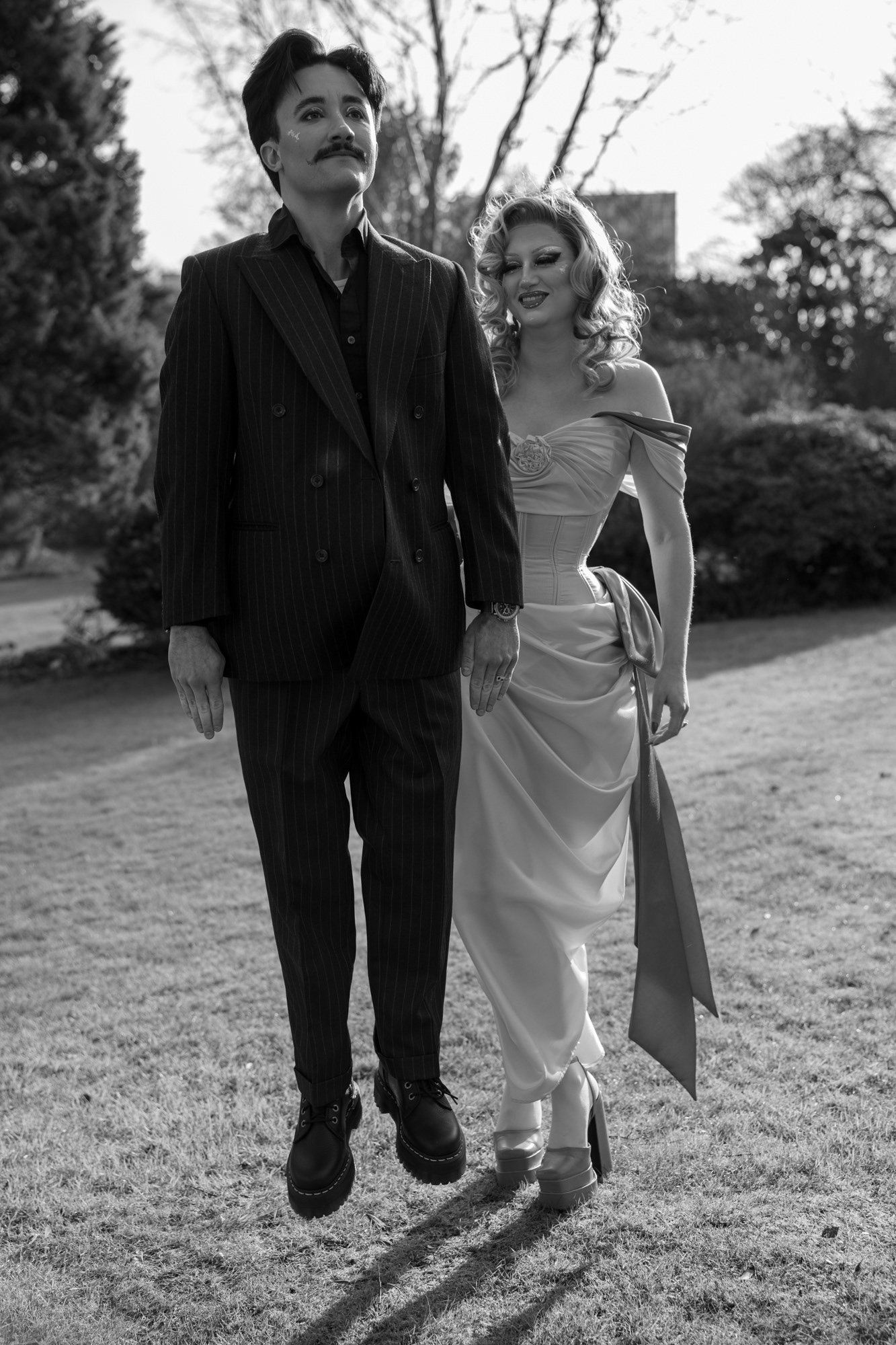 An Aberdeen couple (they/them and she/her) - they are jumping into the air with a straight face and limbs, while she looks on.