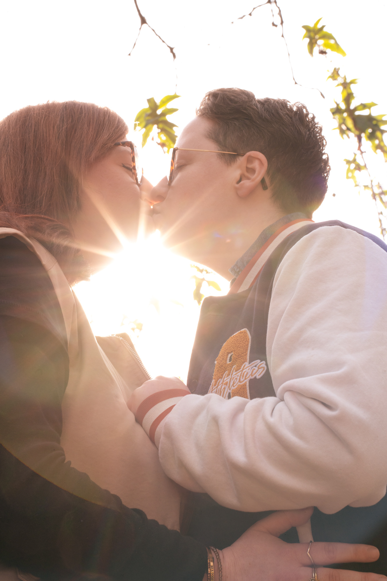 Close up of a queer couple kissing, a sunburst of light shining between them. Taken by Aberdeen wedding photographer, Windswept Stories, during a couple's photo session which would be suitable for an engagement or pre-wedding photo session.
