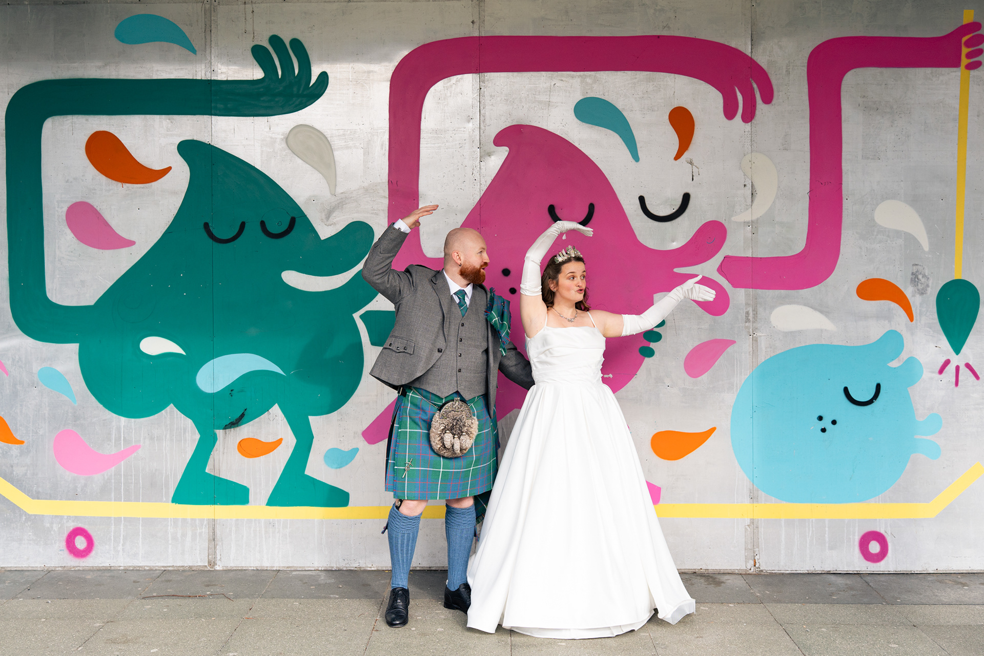 Alternative Aberdeen Wedding Photography: Bride and groom pull silly poses and faces in front of graffiti wall in central Aberdeen.