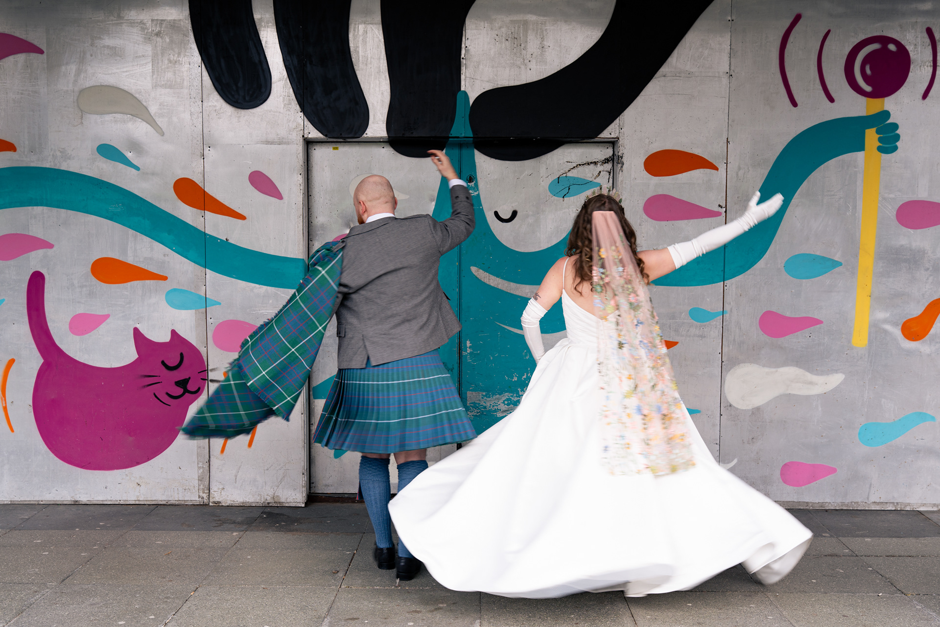 Alternative Aberdeen Wedding Photography: Newlyweds dance in front of graffiti wall.