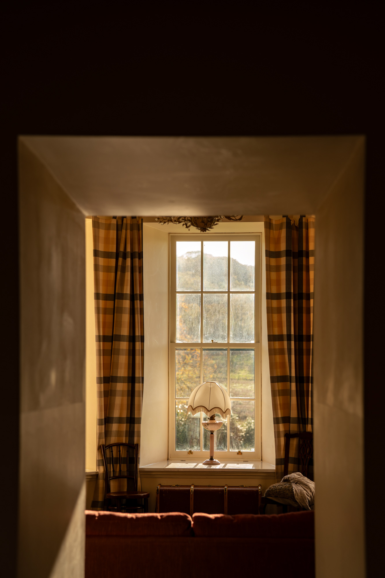 Logie Country House: A lamp sits on a windowsill with tartan curtains around it