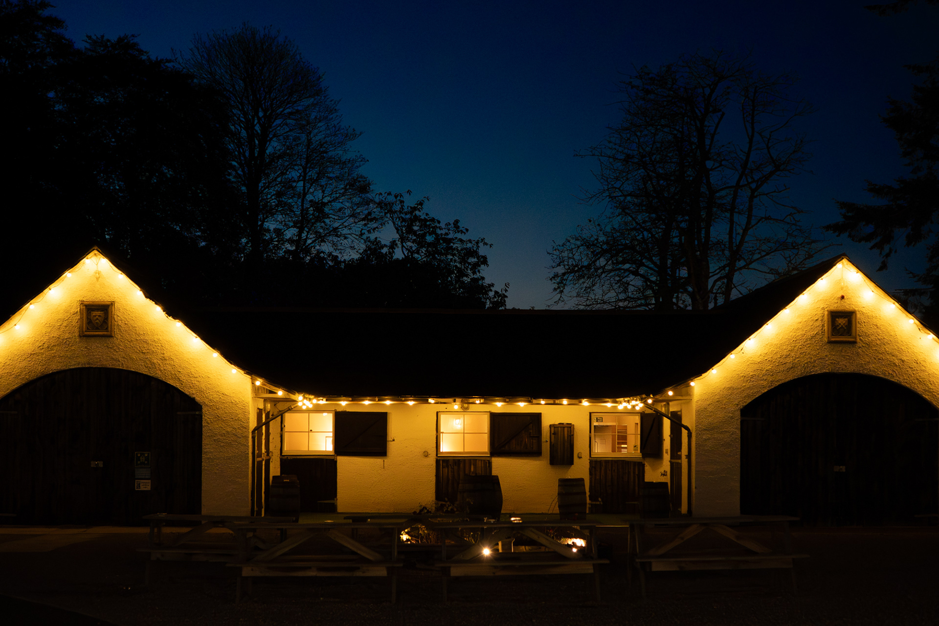 Logie Country House: the steading where wedding receptions are held, glowing orange against a deep blue night sky