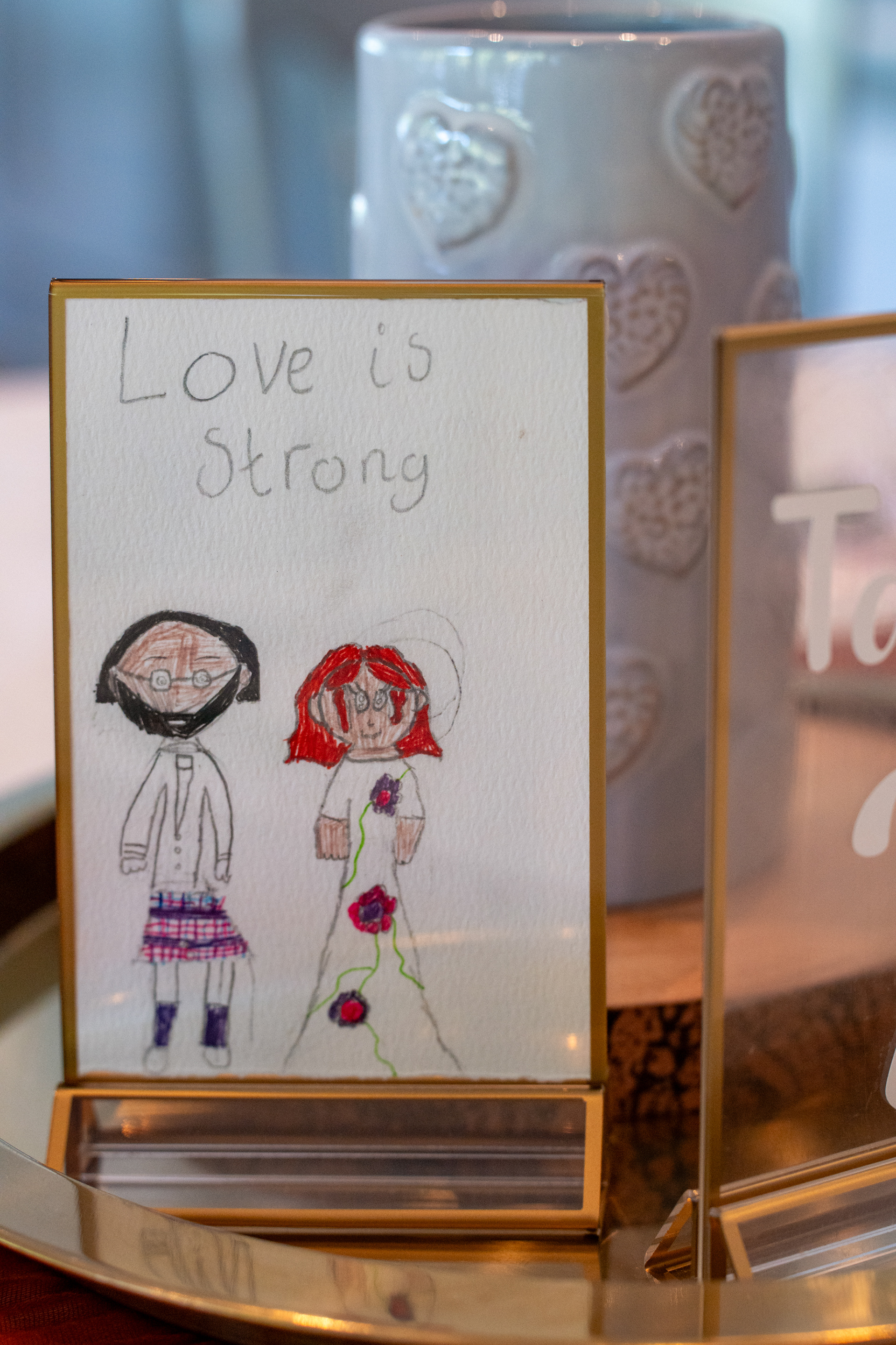 A drawing of the bride and groom, done by a primary four child, is framed and used as a table decoration.