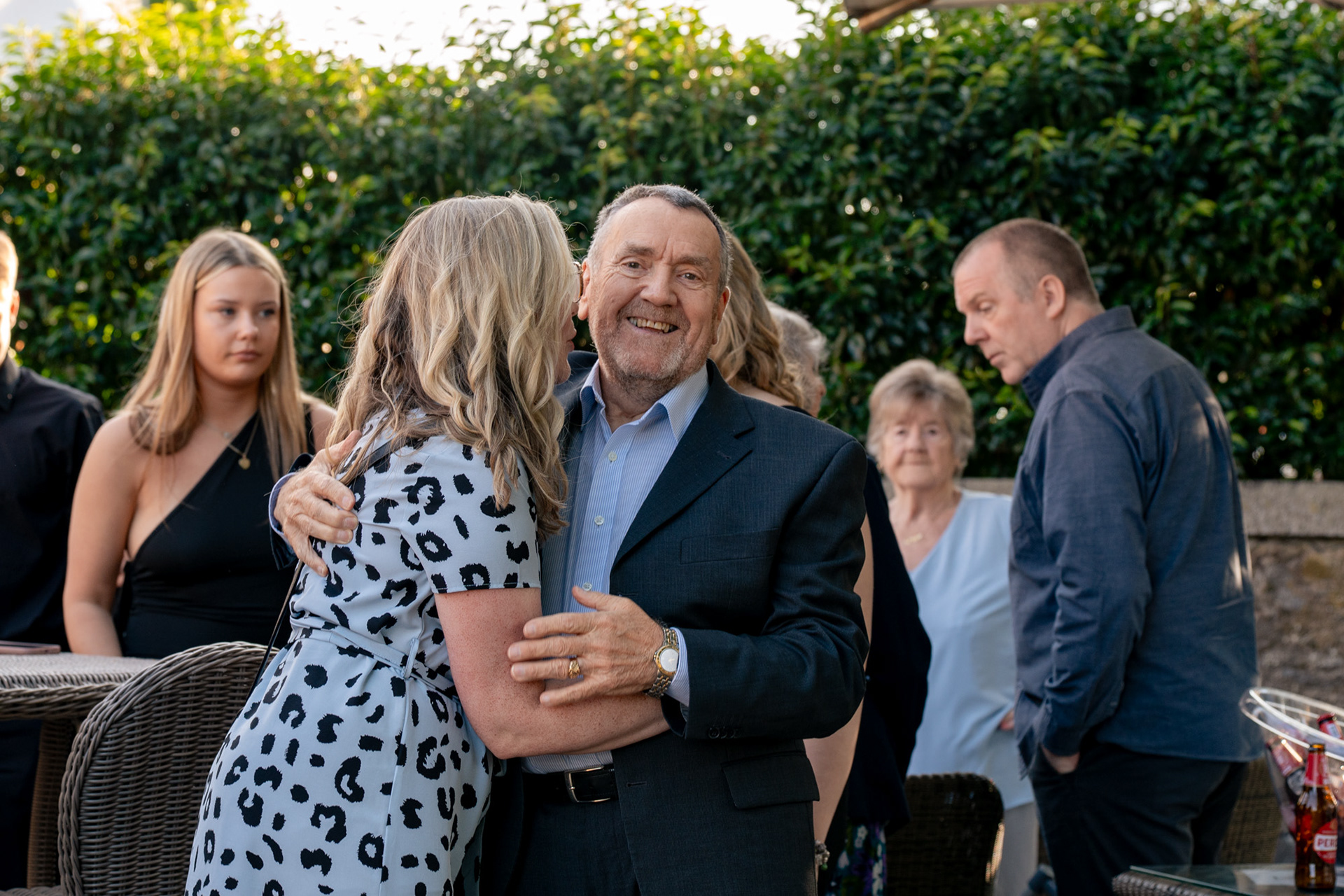 Aberdeen party photography: A blonde woman in pale blue dress hugs her father, also dressed in blue, as he laughs and looks straight at the camera.