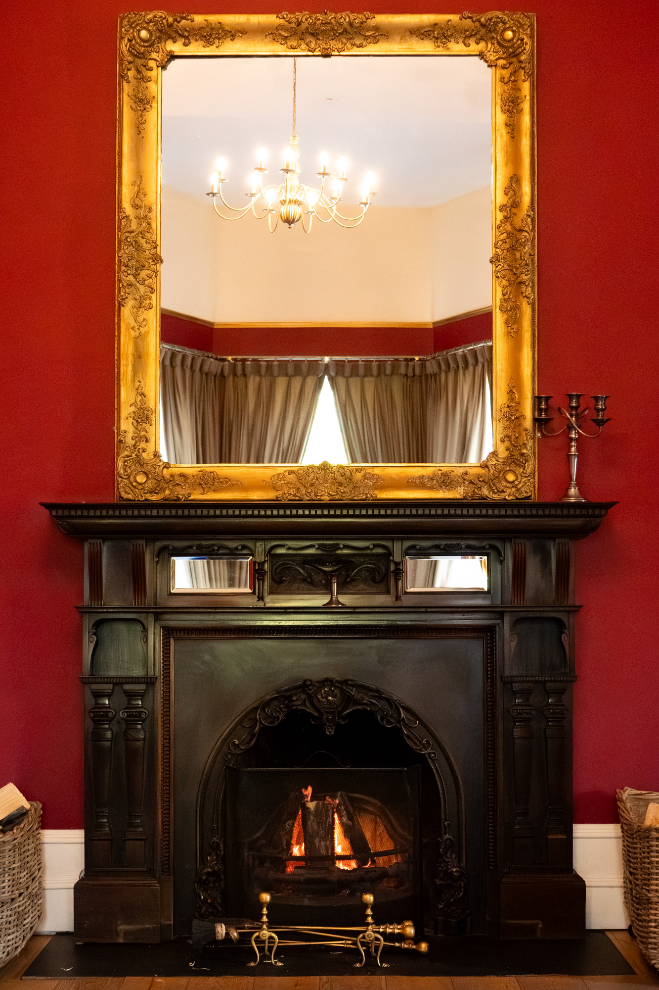 Logie Country House: An ornate mirror sits above a huge black fireplace in a red room